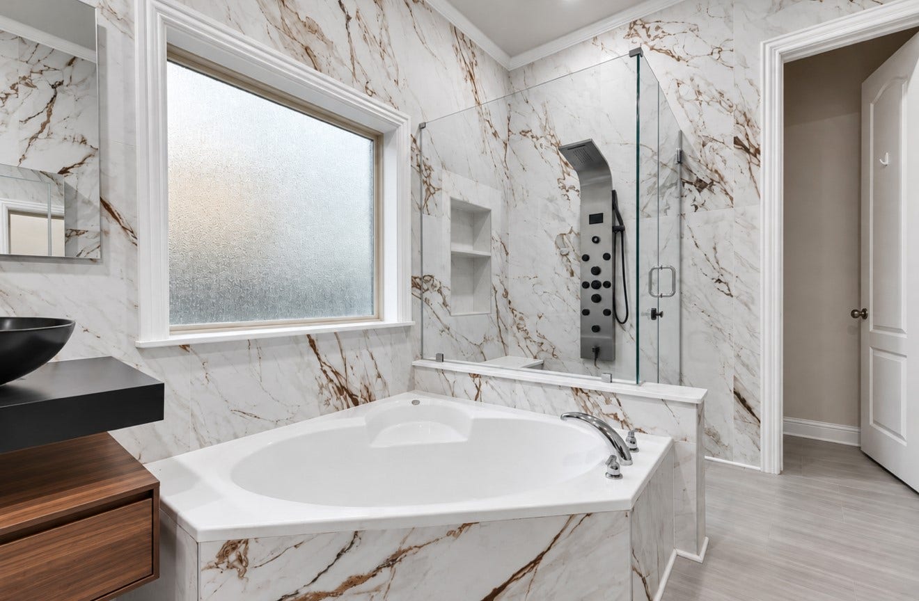 2120 Rosenthal Lane, Houston, TX 77080 Fully renovated primary bathroom featuring striking marble-look finishes, dual floating vanities with vessel sinks, and illuminated mirrors. A soaking tub and separate glass-enclosed shower with a rainfall showerhead, body jets, and handheld sprayer create a luxurious retreat.