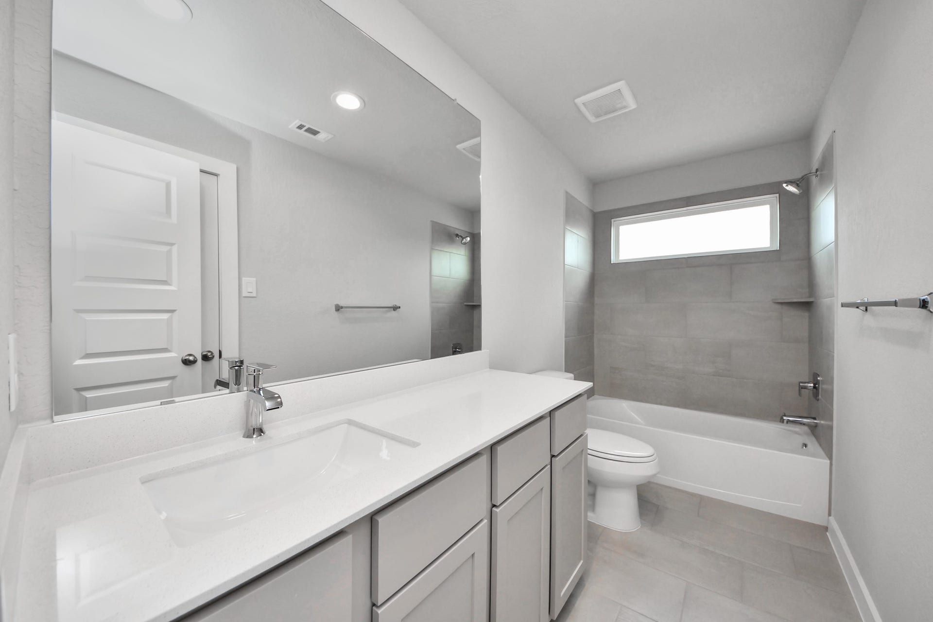 11115 Tulip Ridge Trail, Houston, TX 77044 Secondary bath features tile flooring, bath/shower combo with tile surround, light stained wood cabinets, beautiful light countertop. Sample photo of completed home with similar floor plan. Actual colors and selections may vary.