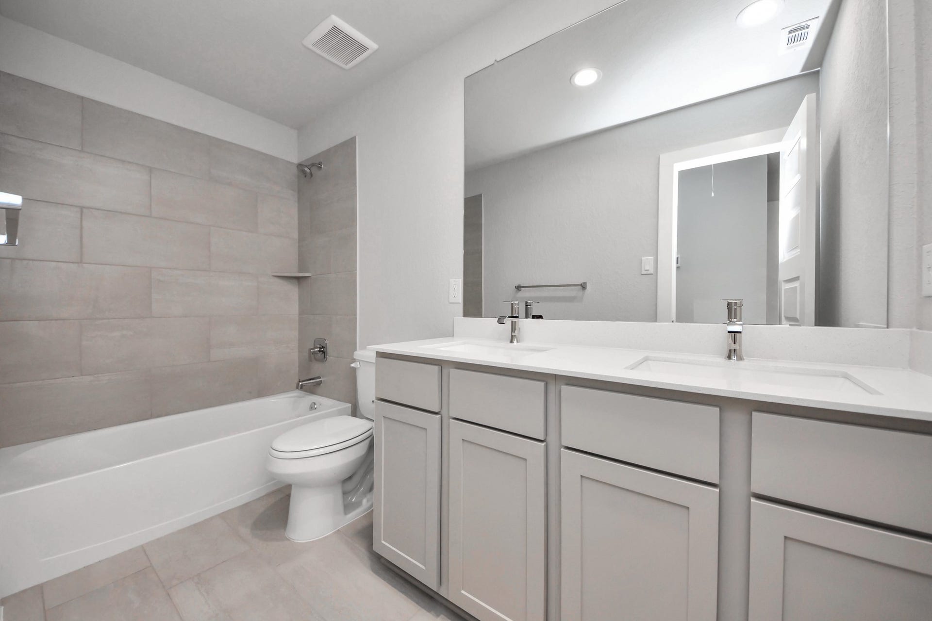 11115 Tulip Ridge Trail, Houston, TX 77044 Secondary bath features tile flooring, bath/shower combo with tile surround, light stained wood cabinets, beautiful light countertop. Sample photo of completed home with similar floor plan. Actual colors and selections may vary.