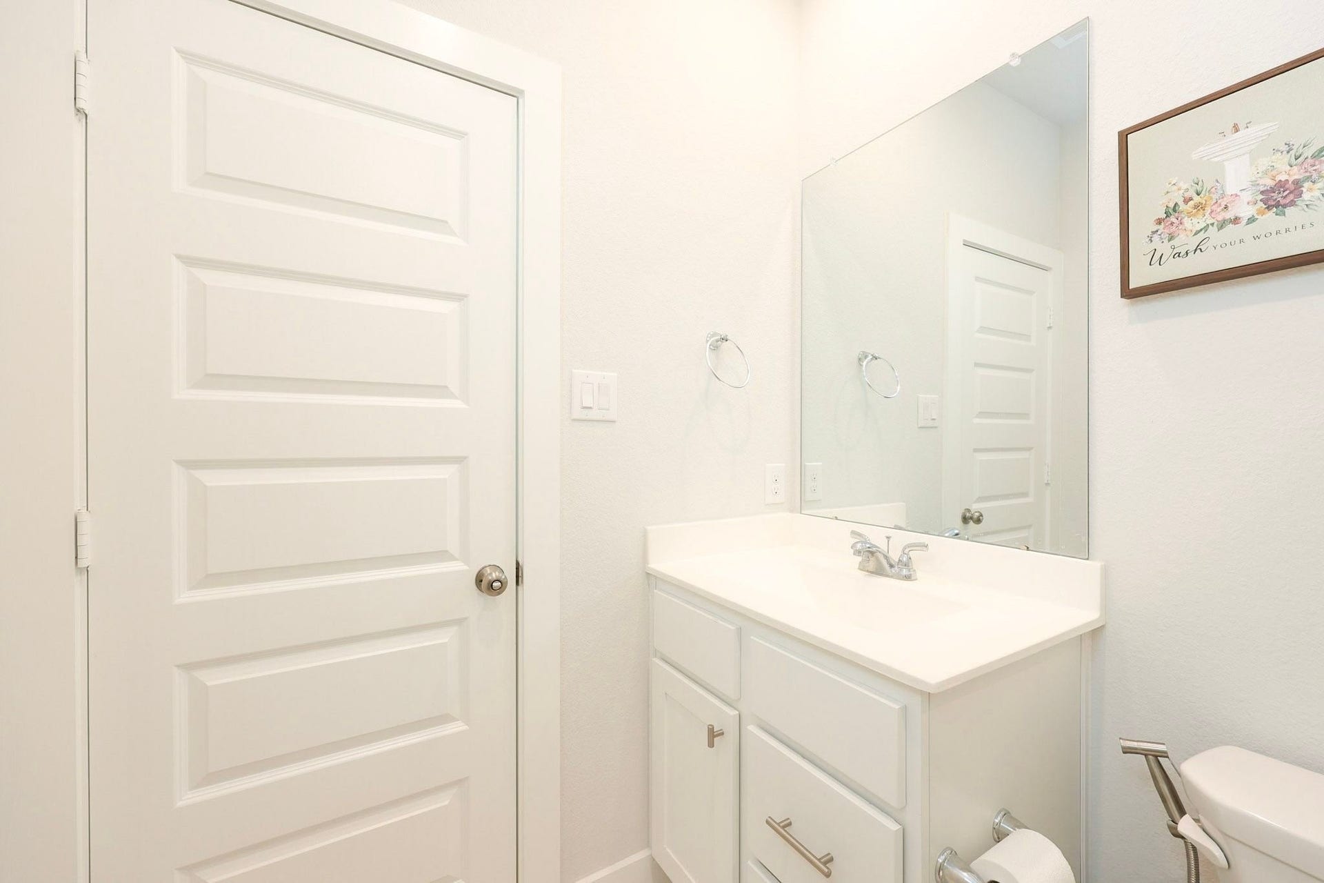 29651 Bur Creek Lane, Fulshear, TX 77441 Secondary bathroom on first floor situated across from secondary bedroom with a sleek vanity, large mirror, and fresh white finishes creating a clean and inviting atmosphere.