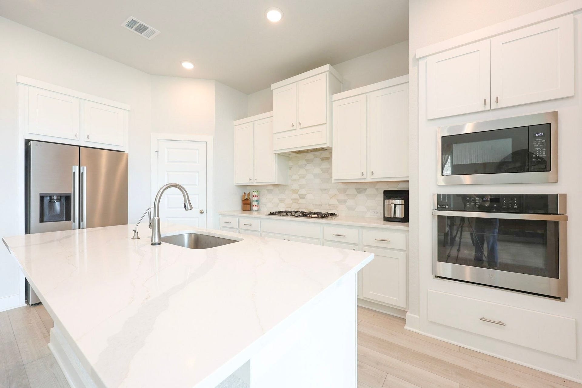 29651 Bur Creek Lane, Fulshear, TX 77441 Open kitchen featuring a spacious quartz island, stainless steel appliances, and ample white cabinetry for storage.