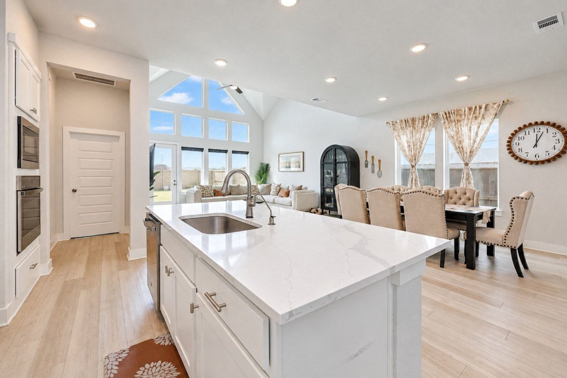 29651 Bur Creek Lane, Fulshear, TX 77441 Open-concept living area featuring a modern kitchen with a large island, elegant dining space, and a spacious seating area, all accented by abundant natural light from floor to ceiling windows.