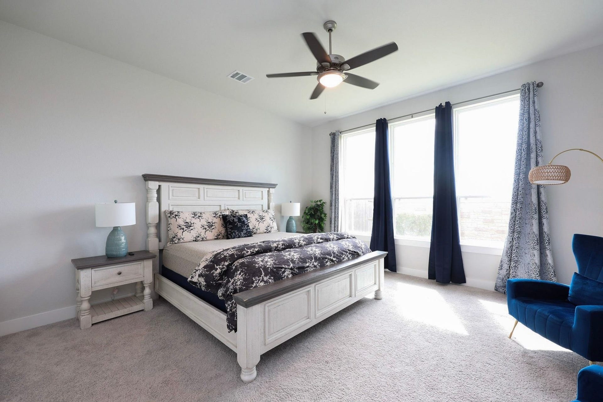29651 Bur Creek Lane, Fulshear, TX 77441 Spacious and bright primary bedroom with floor to ceiling windows, featuring a ceiling fan, elegant window coverings, and plush carpet.