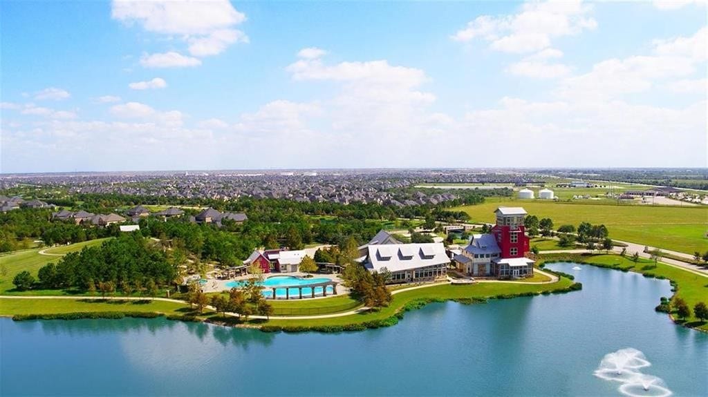 29651 Bur Creek Lane, Fulshear, TX 77441 Experience serene lakeside living with beautiful community amenities, including a spacious pool, lush green spaces, and stunning waterfront views.