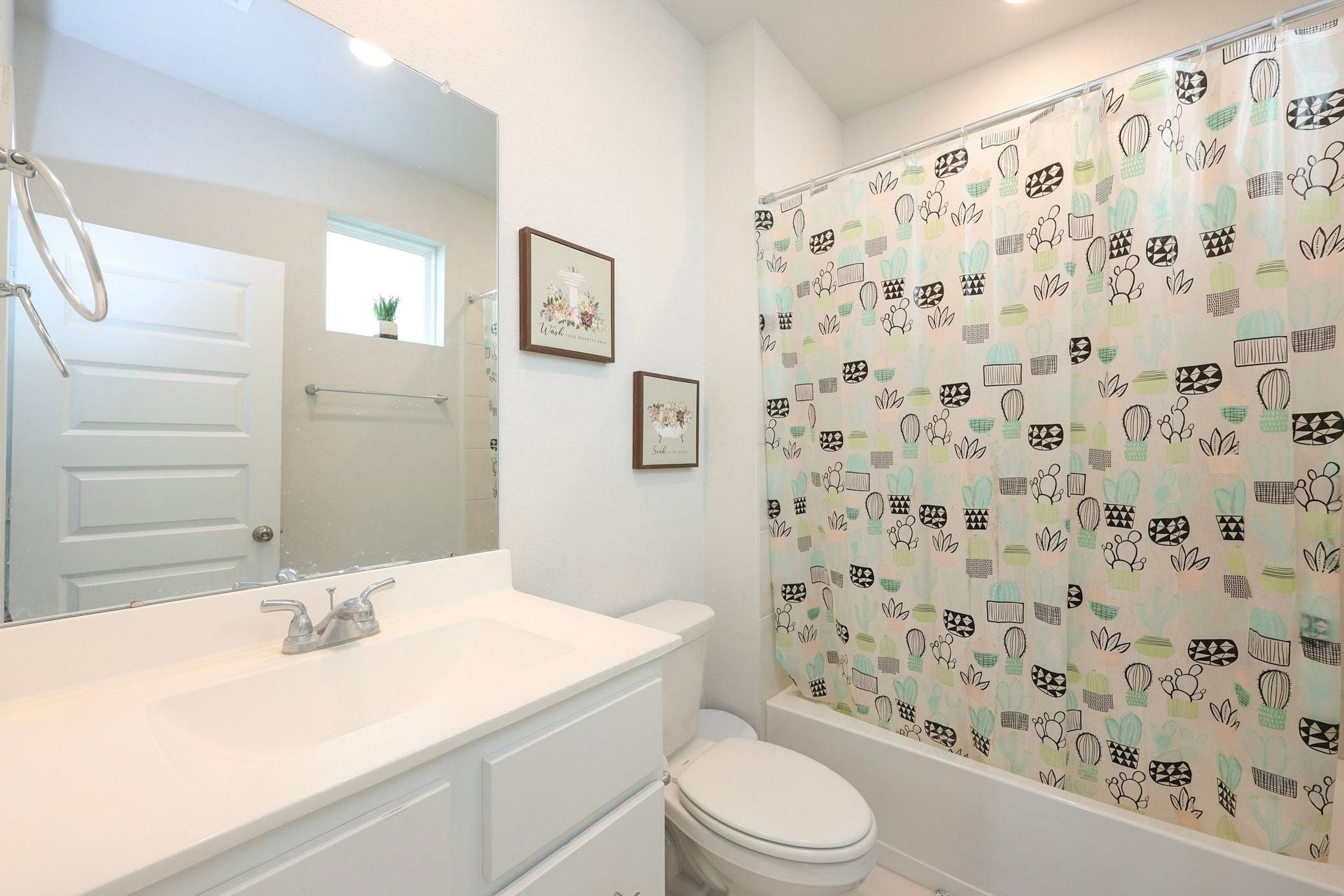 29651 Bur Creek Lane, Fulshear, TX 77441 Secondary bathroom on 1st floor with a window - featuring a sleek white vanity and a tub with shower.