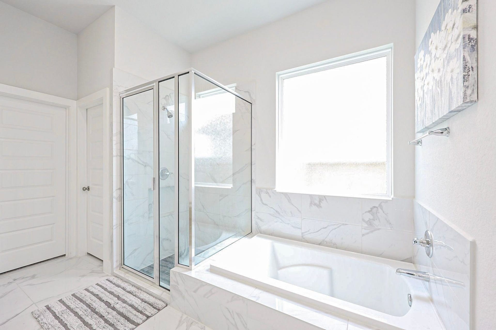29651 Bur Creek Lane, Fulshear, TX 77441 Elegant primary bathroom on first floor featuring a glass-enclosed shower and a luxurious soaking tub, accented with modern marble tiles and abundant natural light.
