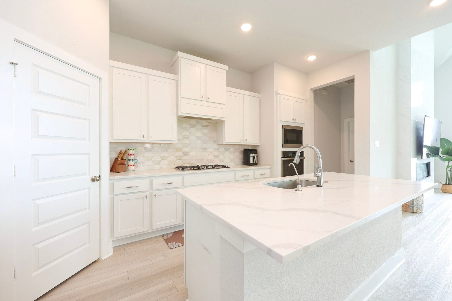 29651 Bur Creek Lane, Fulshear, TX 77441 Modern kitchen featuring sleek white cabinetry, a spacious quartz island with a built-in sink, and stylish backsplash, perfect for culinary enthusiasts.
