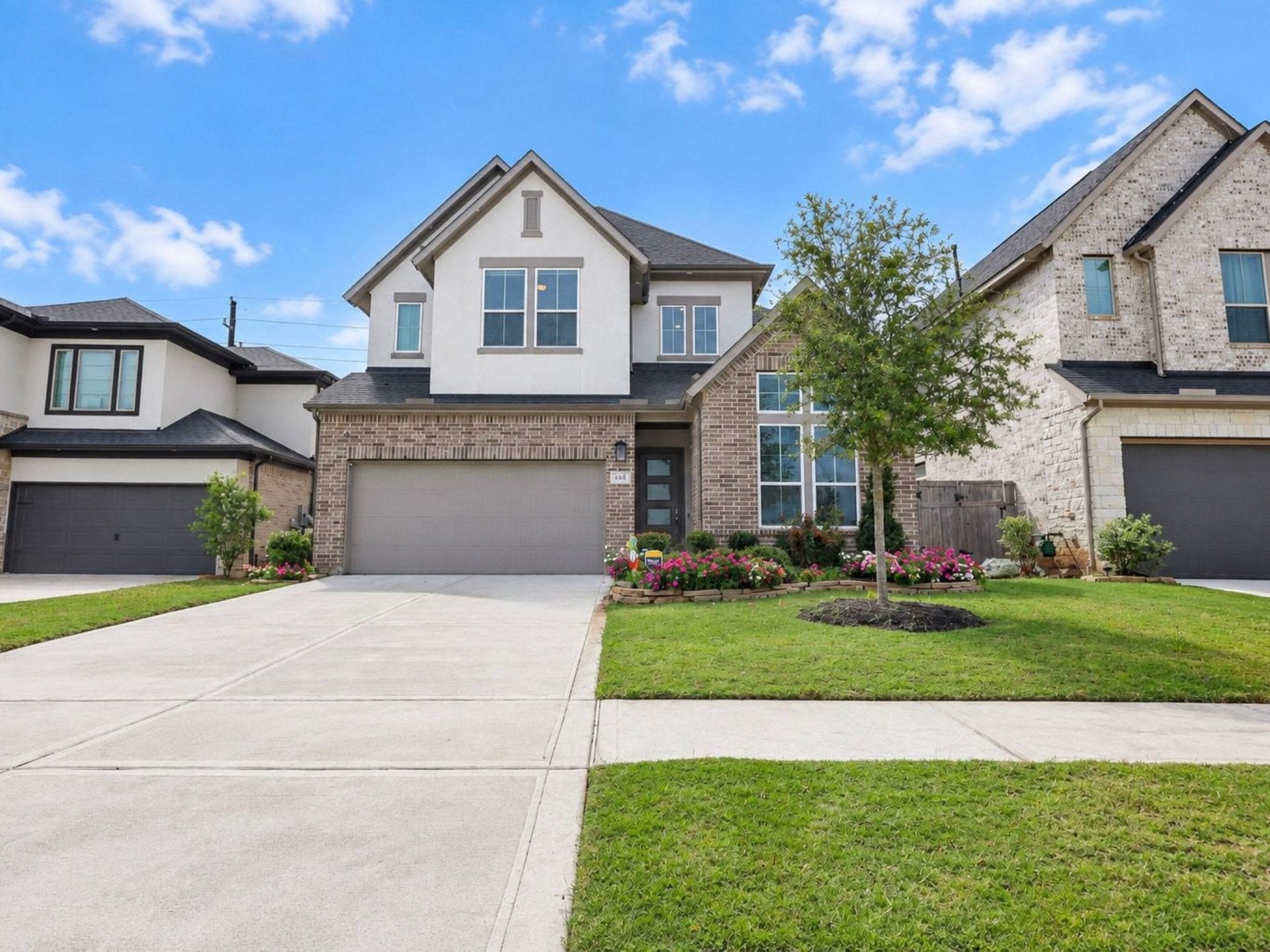 29651 Bur Creek Lane, Fulshear, TX 77441 Charming two-story home with a brick and stuco facade and modern design, featuring a spacious driveway, manicured lawn, and inviting landscaped garden.