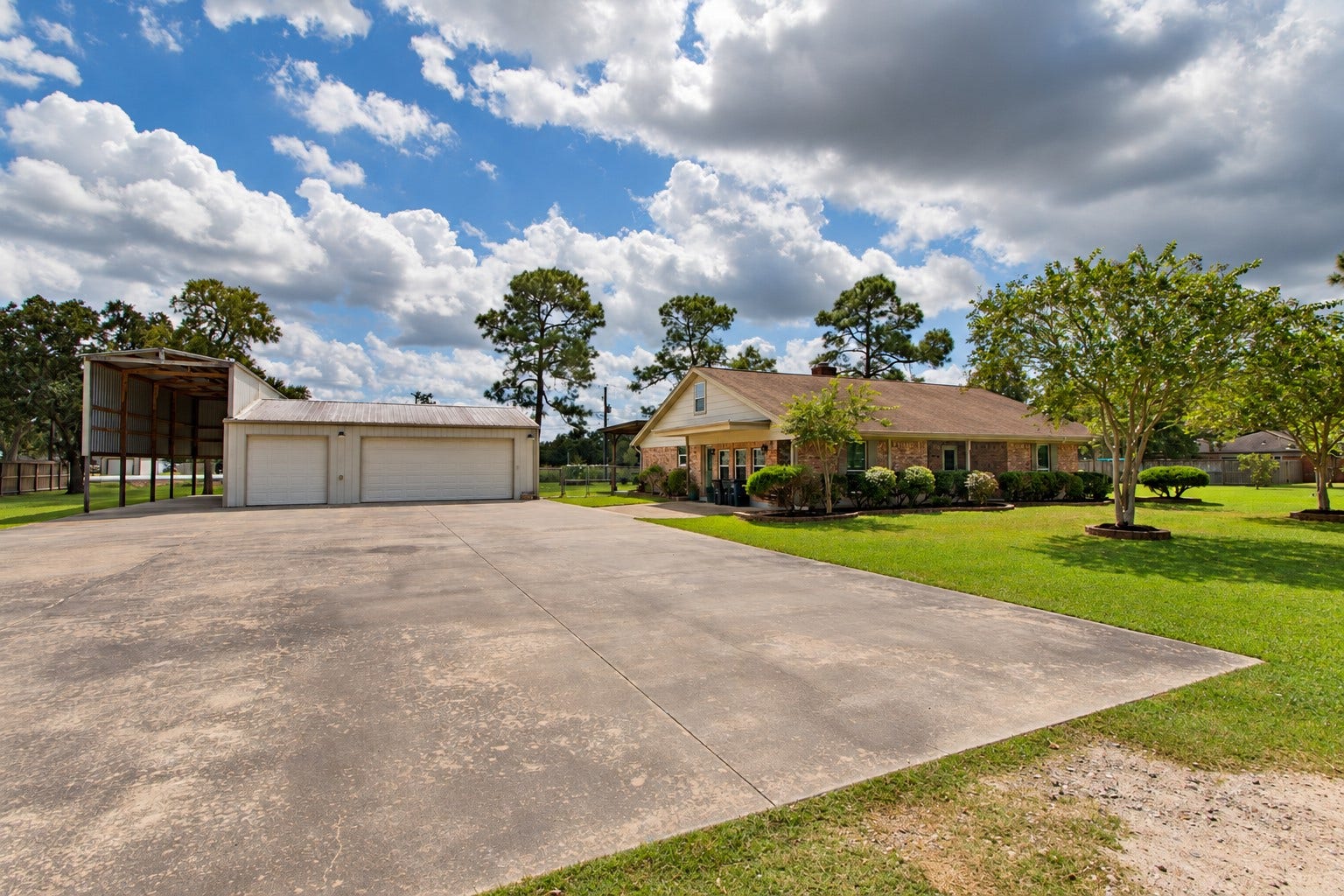 12315 Thaman Drive, Dickinson, TX 77539 Expansive concrete driveway with a spacious garage plus additional covered RV/boat storage, offering plenty of room for vehicles, recreational equipment, and more.