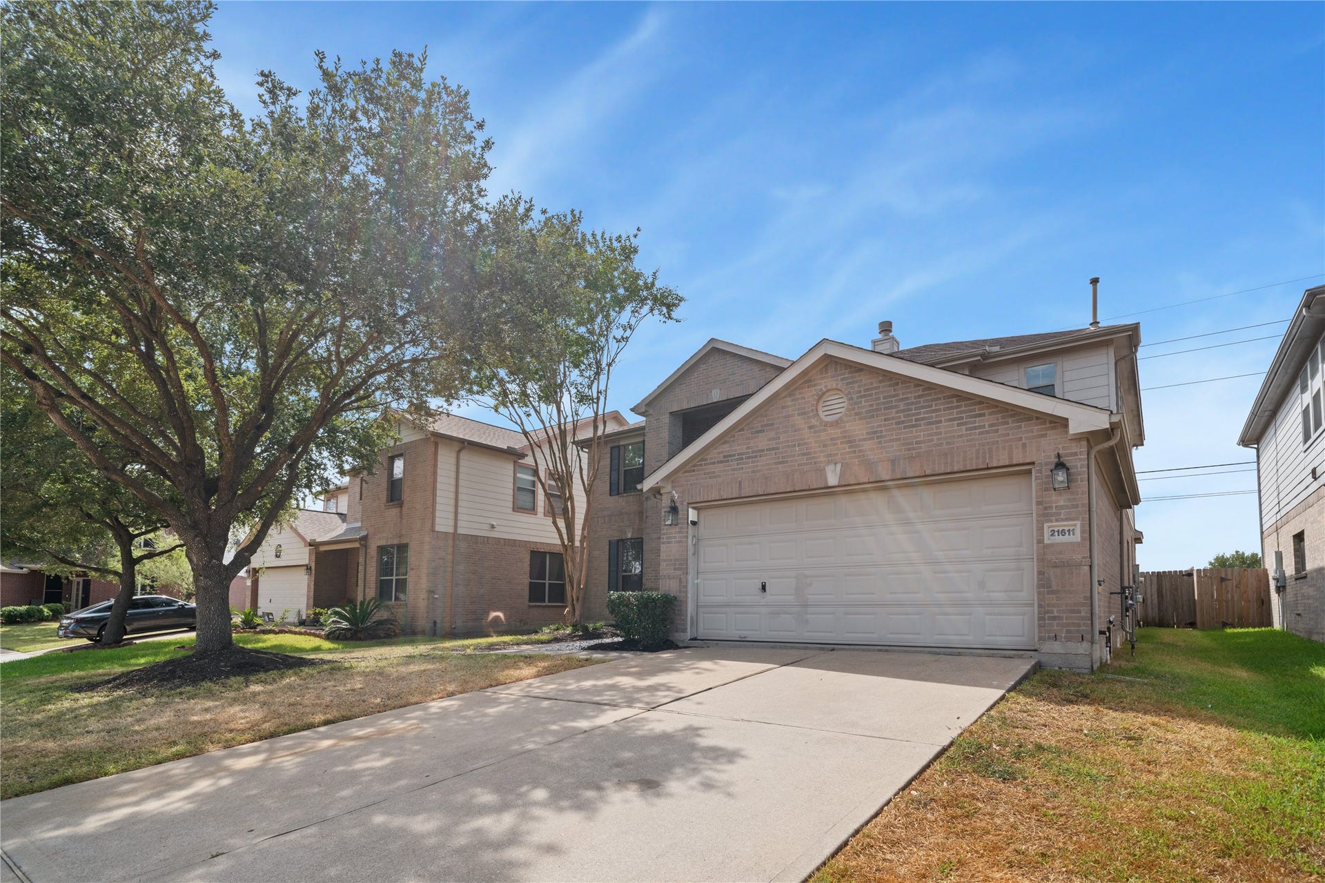 21611 Manitou Falls Lane, Katy, TX 77449 Front Exterior Angled exterior view highlights the brick faade, attached garage and driveway, mature landscaping, and established shade trees.