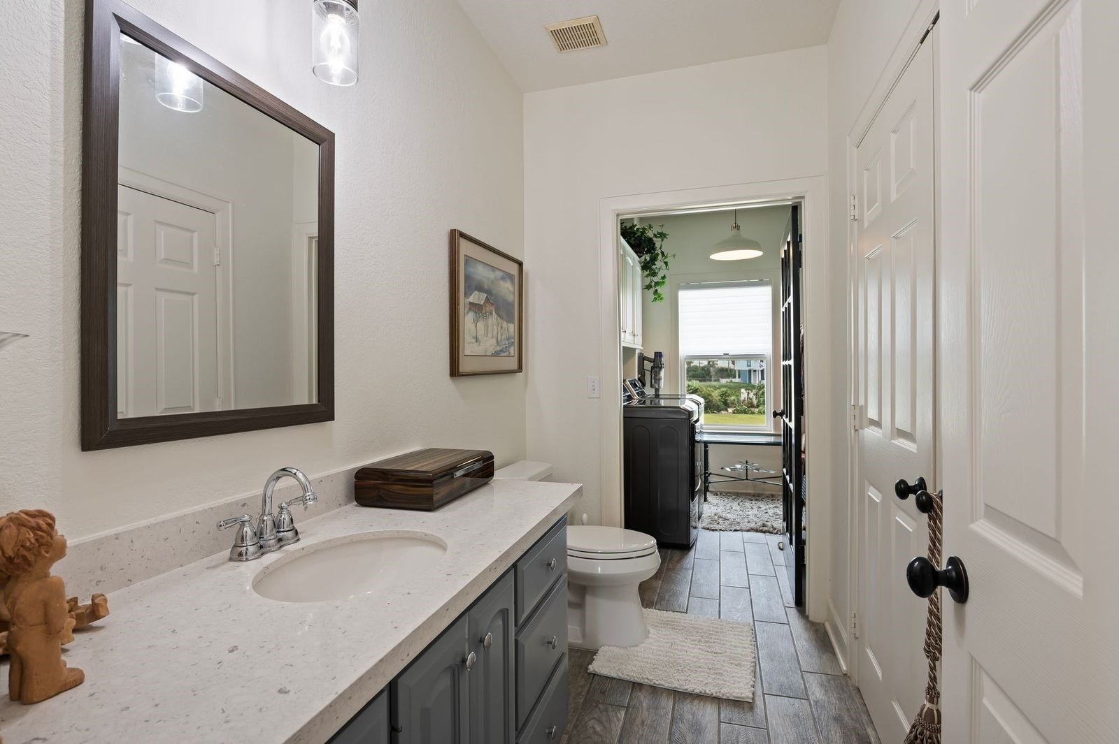 12 Tiki Circle, Tiki Island, TX 77554 Stylish, Elegant & Modern! Convenient half bathroom with custom countertops, storage, framed mirror, custom fixtures and tile flooring.