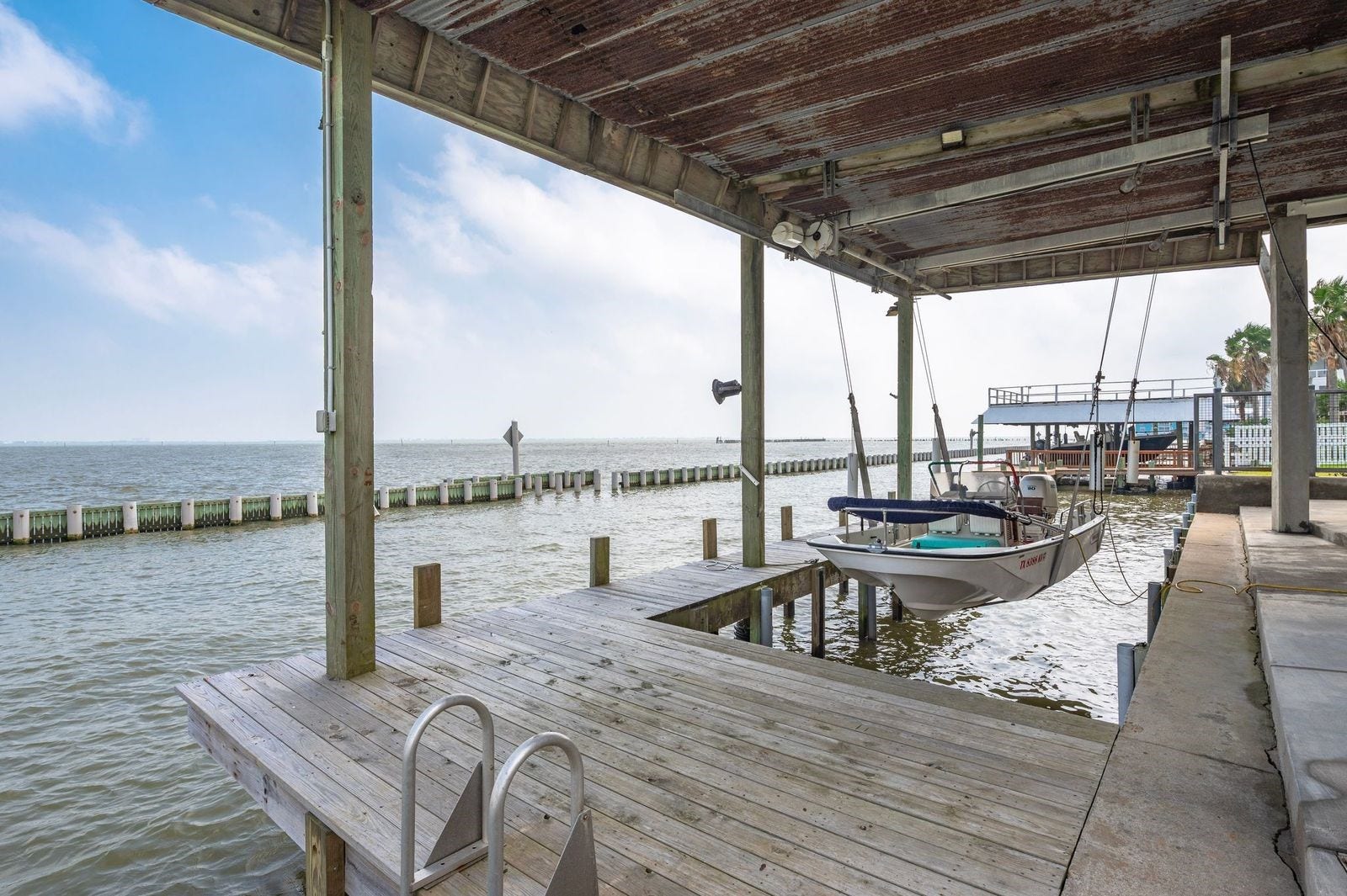 12 Tiki Circle, Tiki Island, TX 77554 Enjoy Your Boat Day or Night! Property boasts concrete bulkhead with boat house/decking and lift featuring 9 "wellers" for the pier; enjoy fishing Galveston Bay with deep water access direct to the Gulf of America.