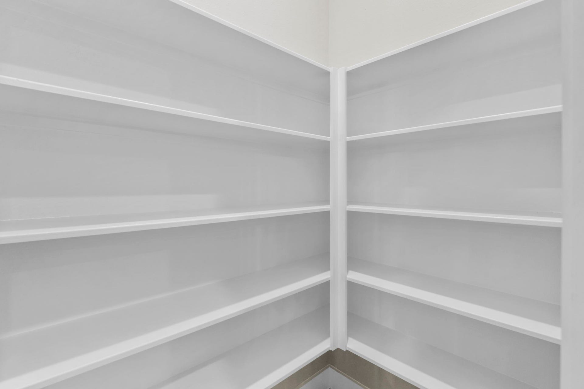 This dedicated walk-in pantry offers exceptional kitchen organization with multi-tiered, wrapped corner shelving.