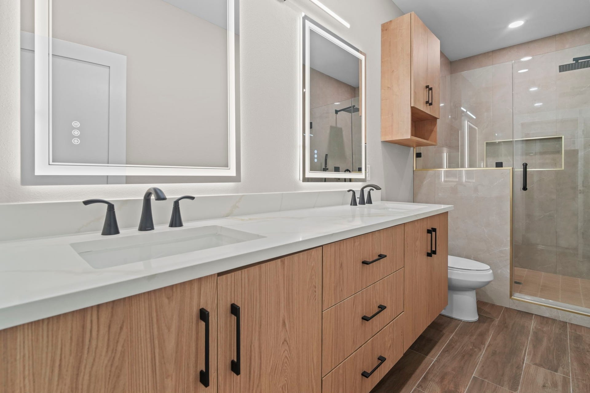 Modern functionality meets elevated design in this primary bath suite. Features include an elongated vanity layout with integrated lighting, dual sinks, and a walk-in glass shower.
