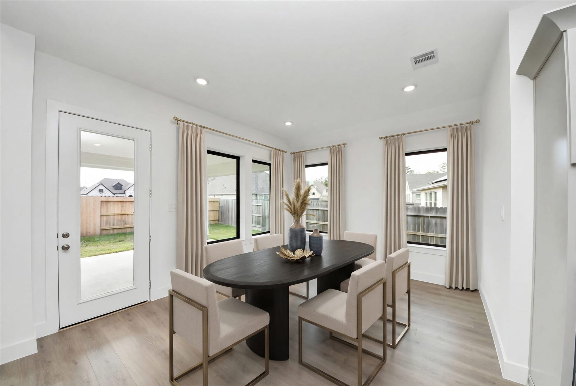 The breakfast room is filled with natural light and features high ceilings, recessed lighting, and expansive windows.