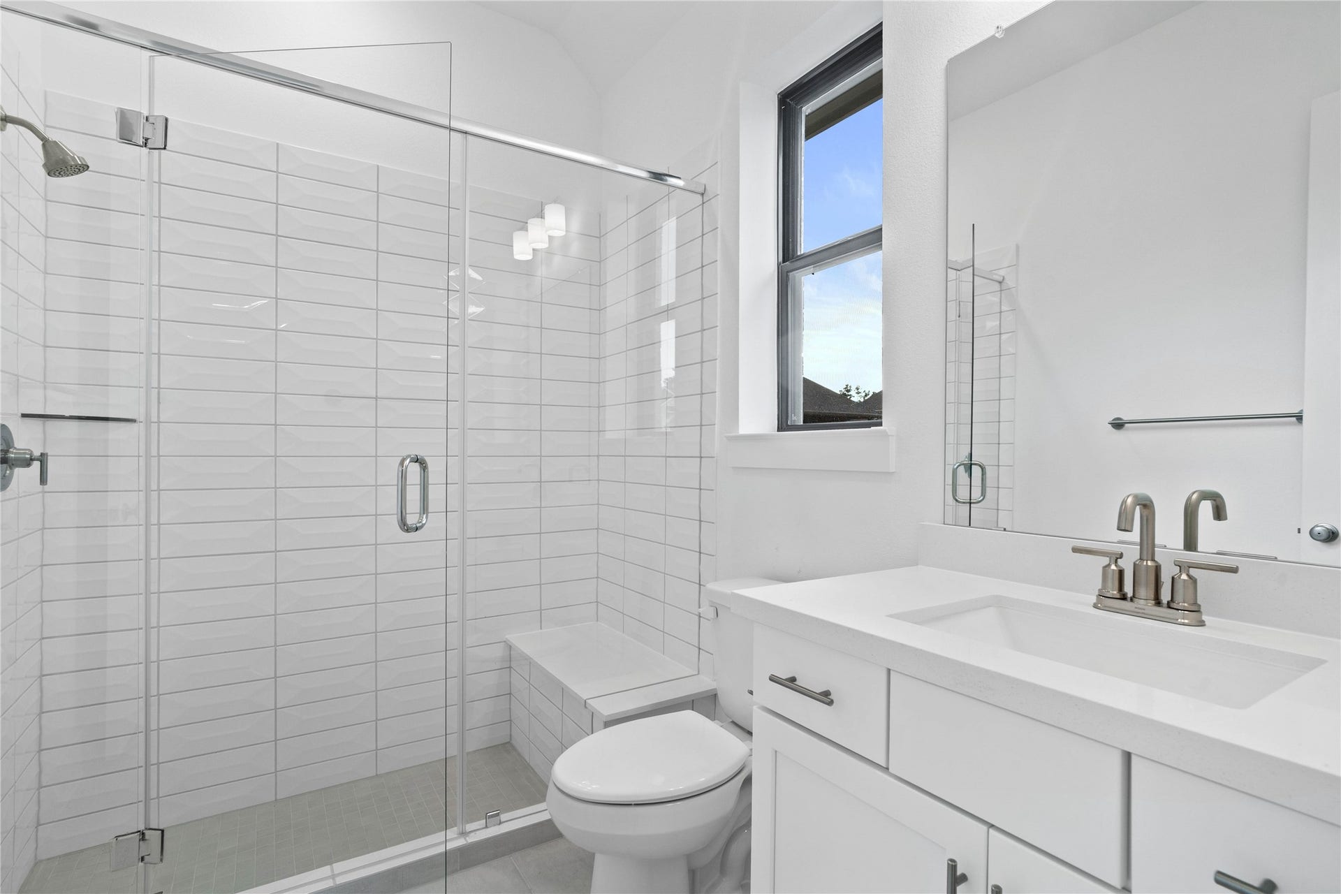 This ensuite secondary bathroom features a modern vanity, large walk-in shower with seat and tile surround, and brushed nickel finishes.