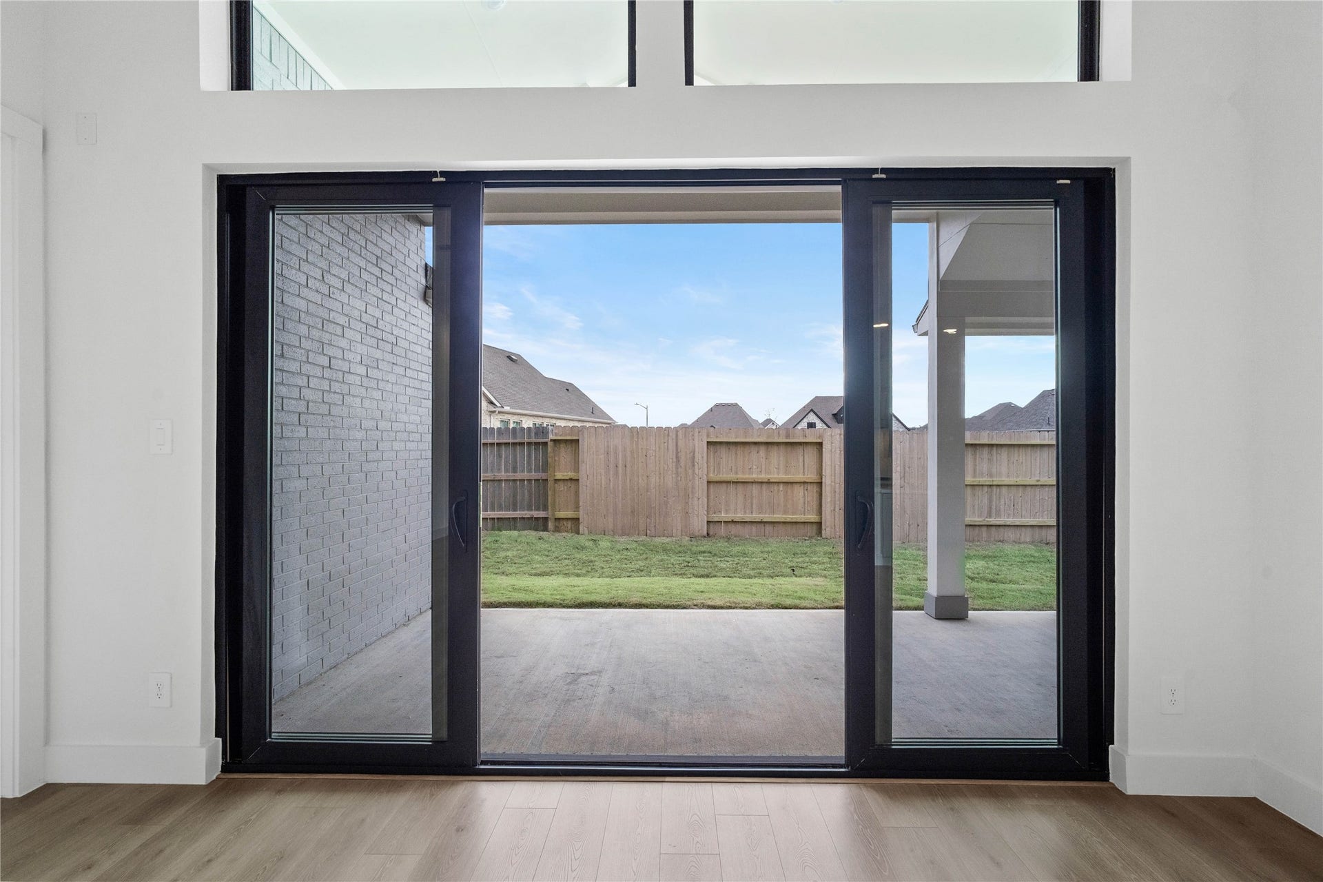 This four-panel multi-slide glass door serves as a stunning architectural focal point, featuring two fixed end panels and two center panels that glide open to create an expansive, unobstructed transition to the patio.