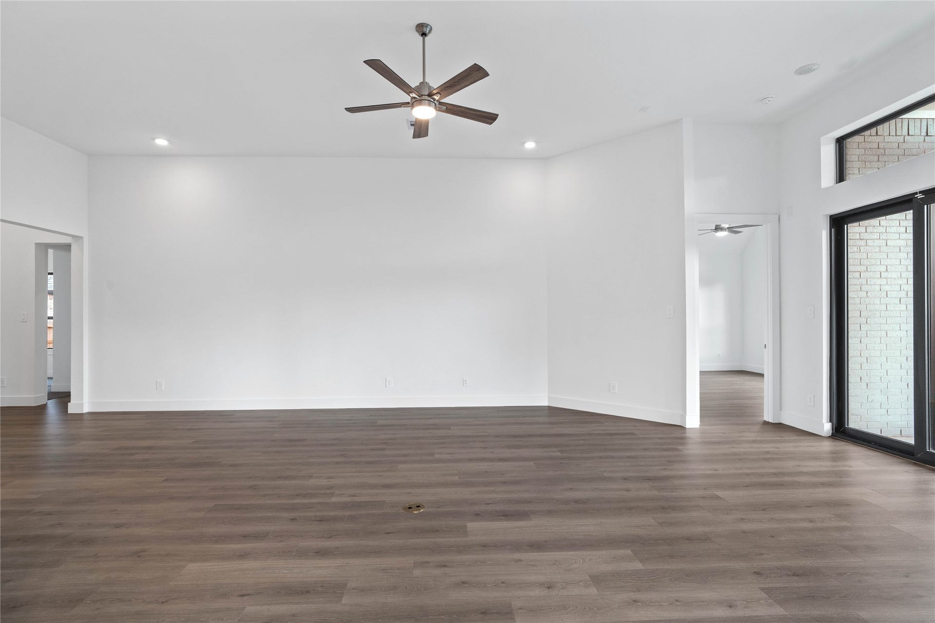 Enjoy the open and airy Family Room, designed for seamless entertaining and showcasing striking architectural details with high ceilings, recessed lighting, durable laminate flooring, and massive glass slider that bring in an abundance of natural light and seamless flow to the covered rear patio.
