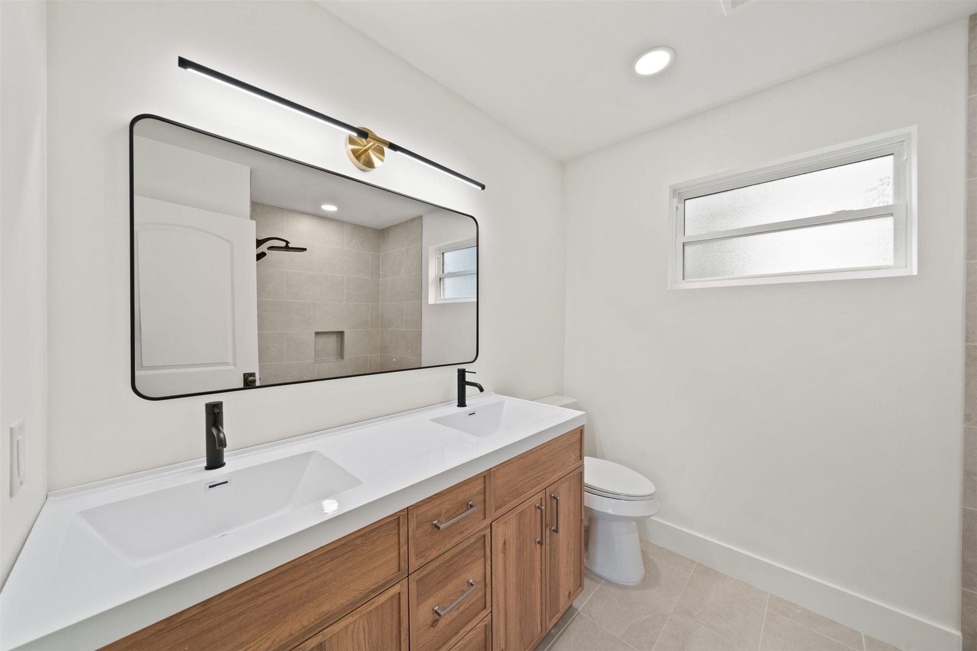 10111 Kerrwood Lane, Houston, TX 77080 The secondary bathroom features a spacious dual-sink vanity, warm wood cabinetry, sleek black fixtures, and beautiful tilework for a clean, modern aesthetic.