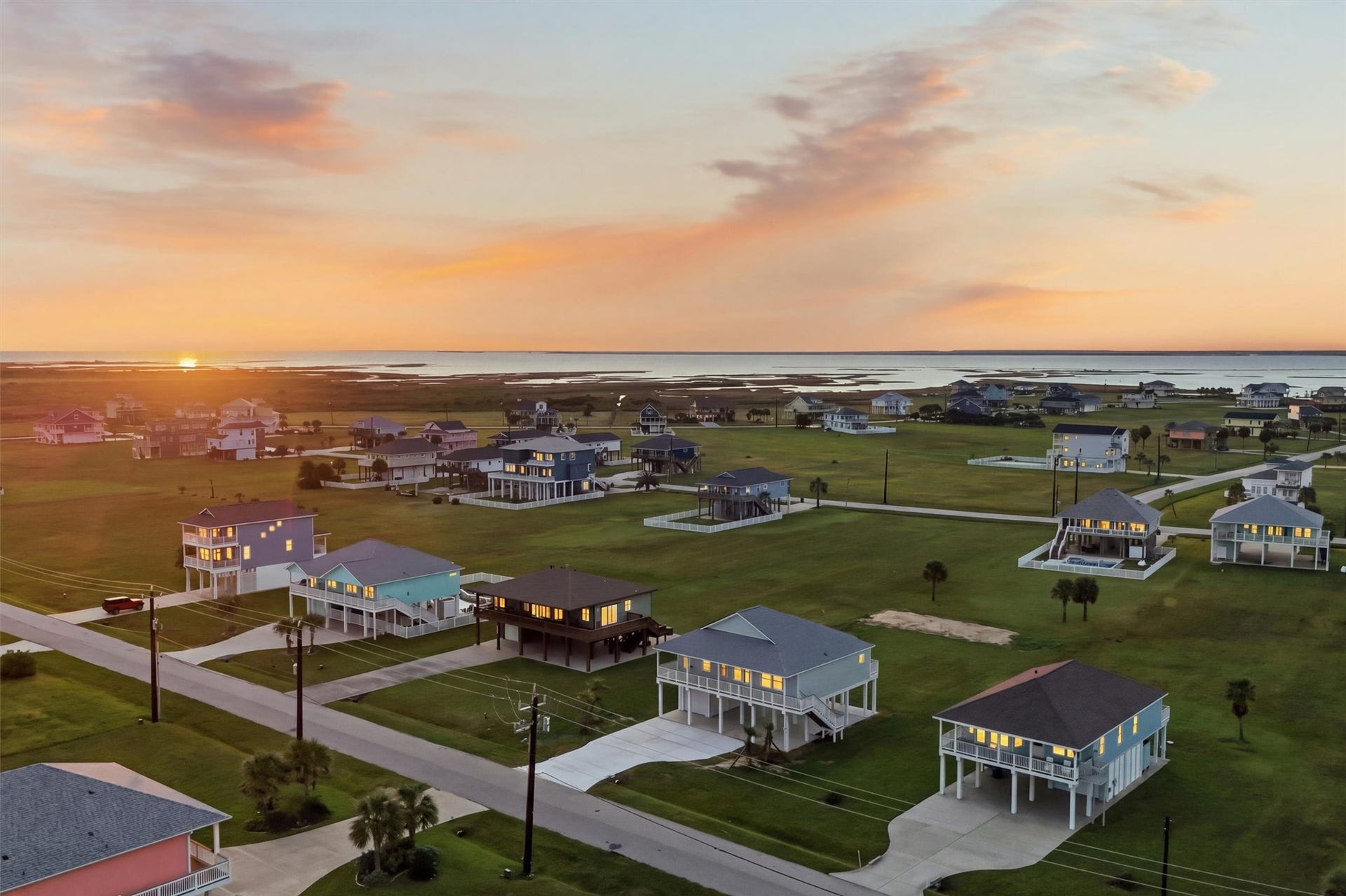 18618 Shaman Drive, Galveston, TX 77554 Charming coastal community with elevated homes, offering stunning sunset views over the water and expansive green spaces.