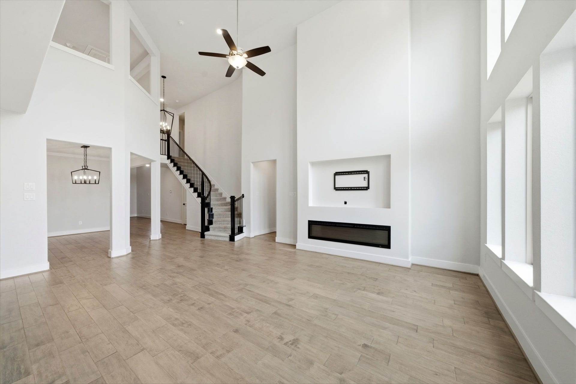 8815 Morning Glow Drive, Missouri City, TX 77459 This spacious living area features high ceilings, large windows for ample natural light, a modern fireplace, and a stylish open staircase. The open layout and neutral tones create a bright, inviting atmosphere perfect for entertaining or relaxing.