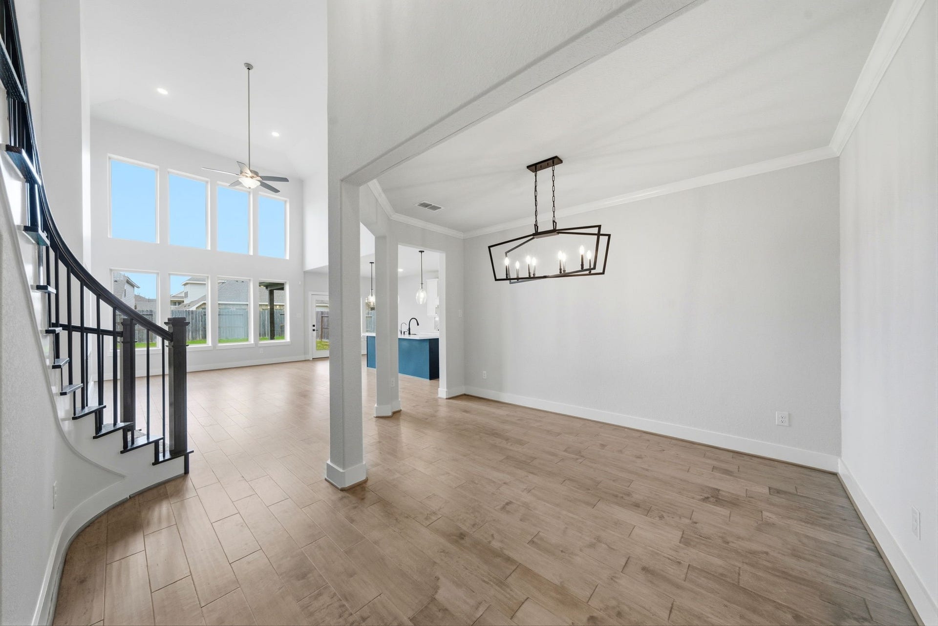 8815 Morning Glow Drive, Missouri City, TX 77459 This spacious home features an open floor plan with high ceilings, large windows for abundant natural light, and elegant wood flooring. The modern chandelier illuminates the dining area, and a curved staircase adds architectural interest.
