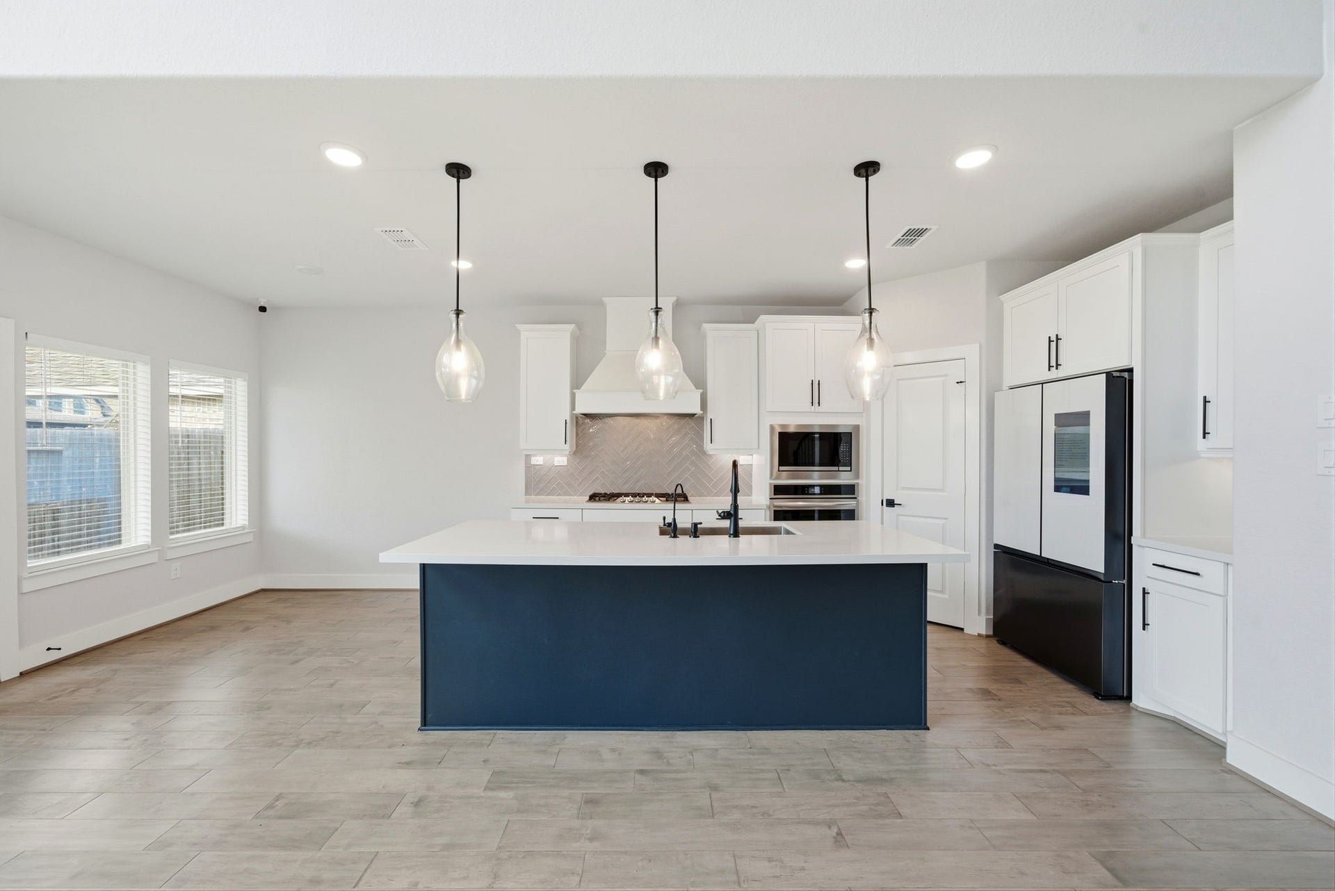 8815 Morning Glow Drive, Missouri City, TX 77459 This modern kitchen features a spacious island with pendant lighting, sleek white cabinetry, and stainless steel appliances. The open layout and large windows provide ample natural light, creating a bright and inviting space.