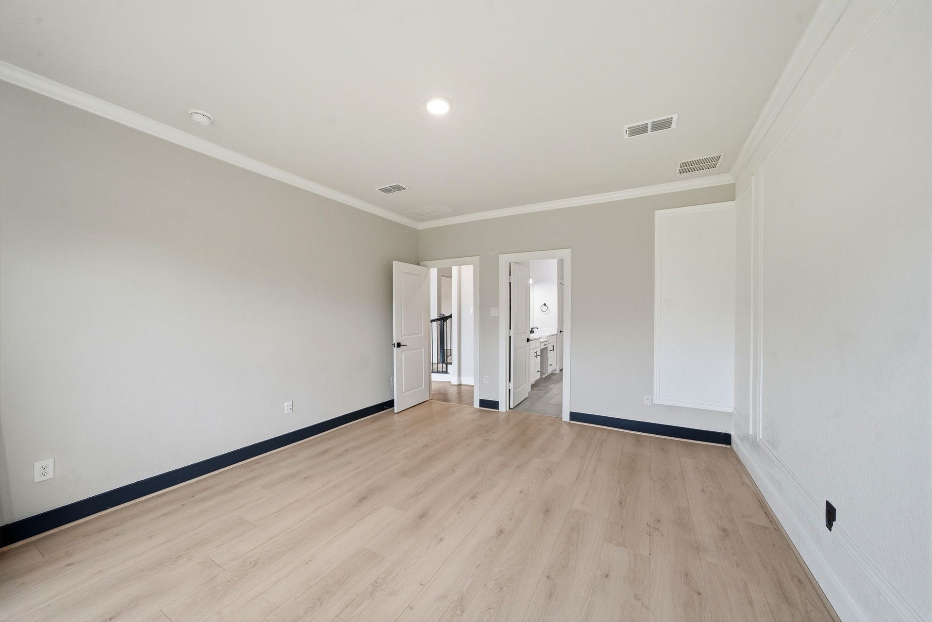 8815 Morning Glow Drive, Missouri City, TX 77459 This room features light wood flooring, neutral gray walls, and recessed lighting. It has a doorway leading to a bathroom, offering a spacious and modern feel.
