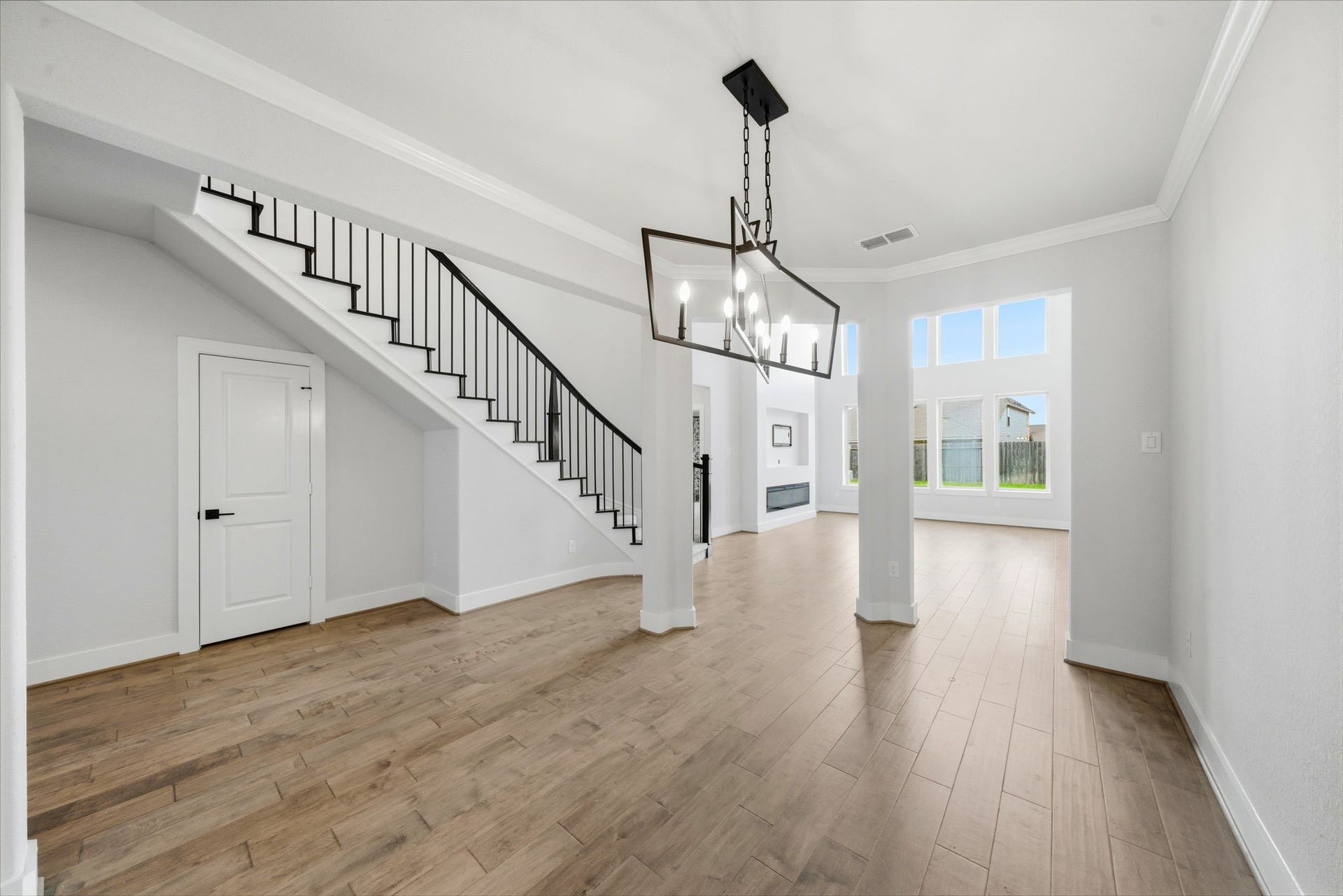 8815 Morning Glow Drive, Missouri City, TX 77459 This bright, open-concept living area features hardwood floors, a modern chandelier, and large windows that provide ample natural light. The staircase with sleek railing adds a contemporary touch, and there's a view into the spacious, inviting room beyond.