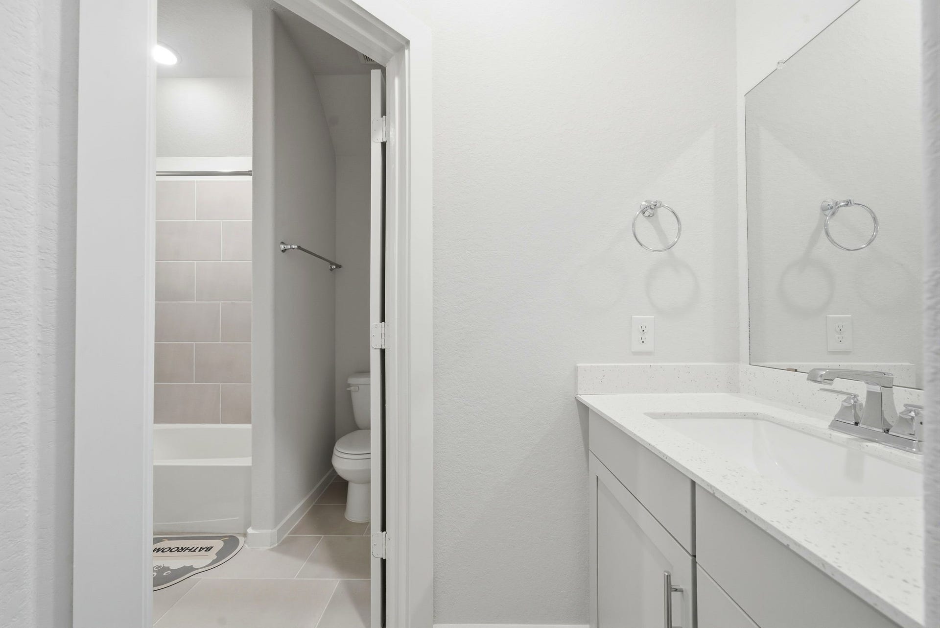 8815 Morning Glow Drive, Missouri City, TX 77459 This photo shows a modern, bright bathroom with a white vanity, large mirror, and a shower-tub combo. The space is clean and minimalistic, featuring neutral tones and contemporary fixtures.