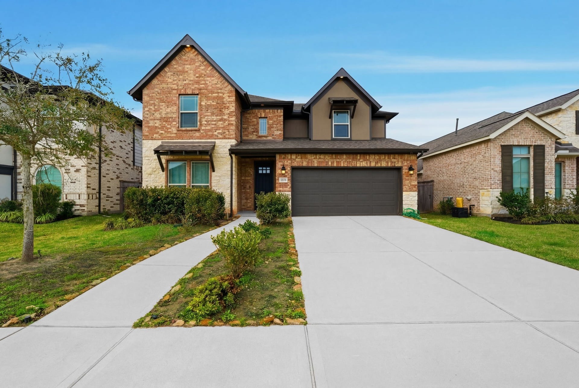 8815 Morning Glow Drive, Missouri City, TX 77459 This photo features a modern two-story brick home with a clean, well-maintained exterior. It has a double garage, a neat driveway, and a small front yard with shrubs and a tree, offering a welcoming curb appeal.