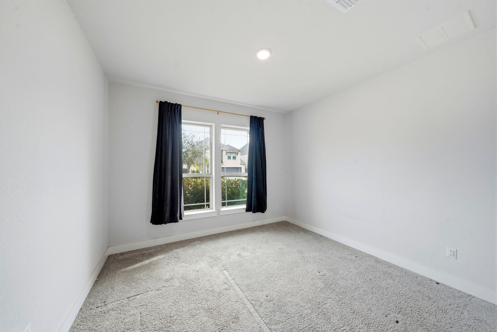 8815 Morning Glow Drive, Missouri City, TX 77459 This room features neutral walls, a large window with dark curtains, and ample natural light. The carpeted floor adds a cozy touch, making it a versatile space for various uses.