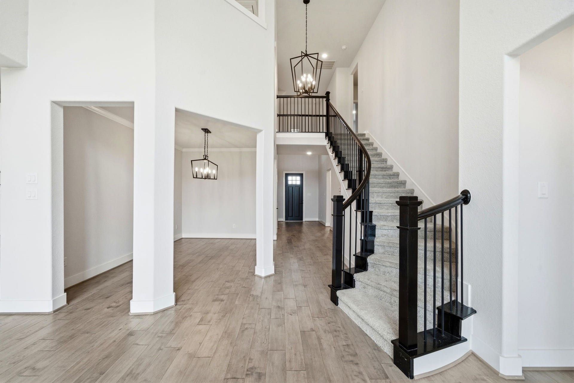 8815 Morning Glow Drive, Missouri City, TX 77459 This spacious entryway features a high ceiling and elegant staircase with wrought-iron railings. The open layout includes a dining area with modern lighting and wood-style flooring, creating a welcoming and stylish atmosphere.