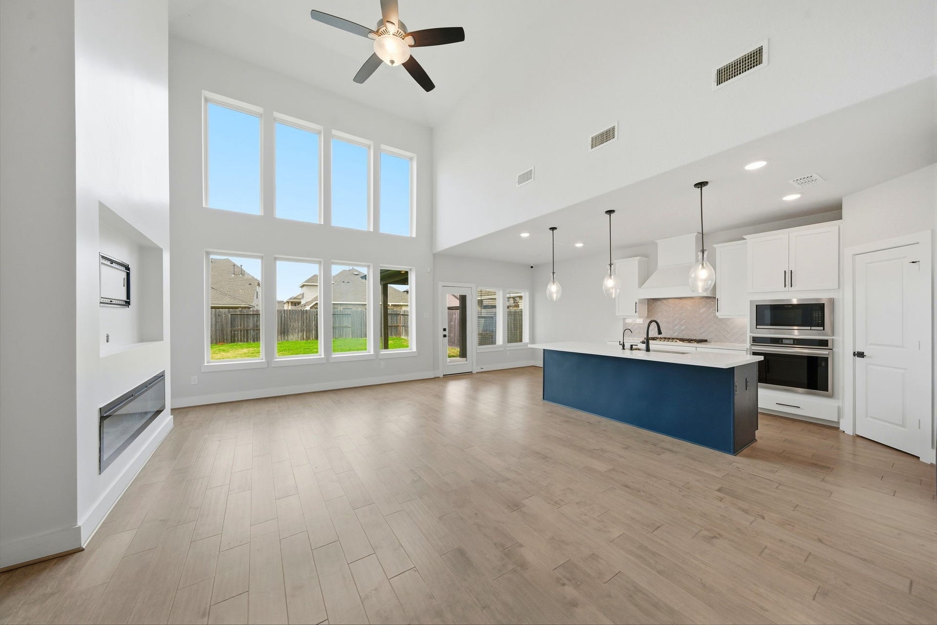 8815 Morning Glow Drive, Missouri City, TX 77459 This spacious open-concept living area features high ceilings, large windows for natural light, a modern kitchen with a stylish island, and hardwood flooring. Perfect for entertaining and family living.