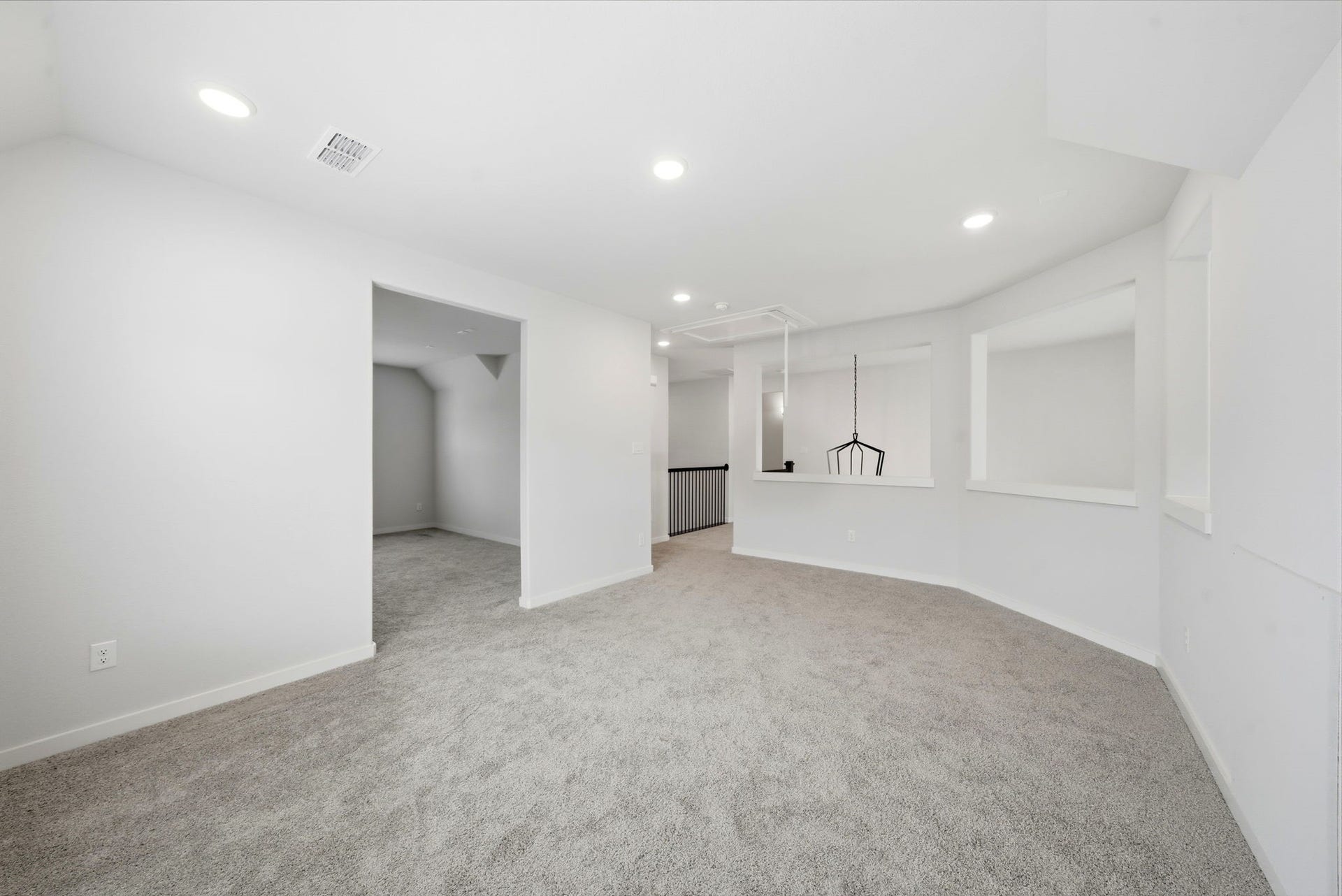 8815 Morning Glow Drive, Missouri City, TX 77459 This photo showcases a spacious, carpeted room with white walls and recessed lighting. It features an open layout with a view of an adjacent space through a wide doorway, perfect for a family room or entertainment area.