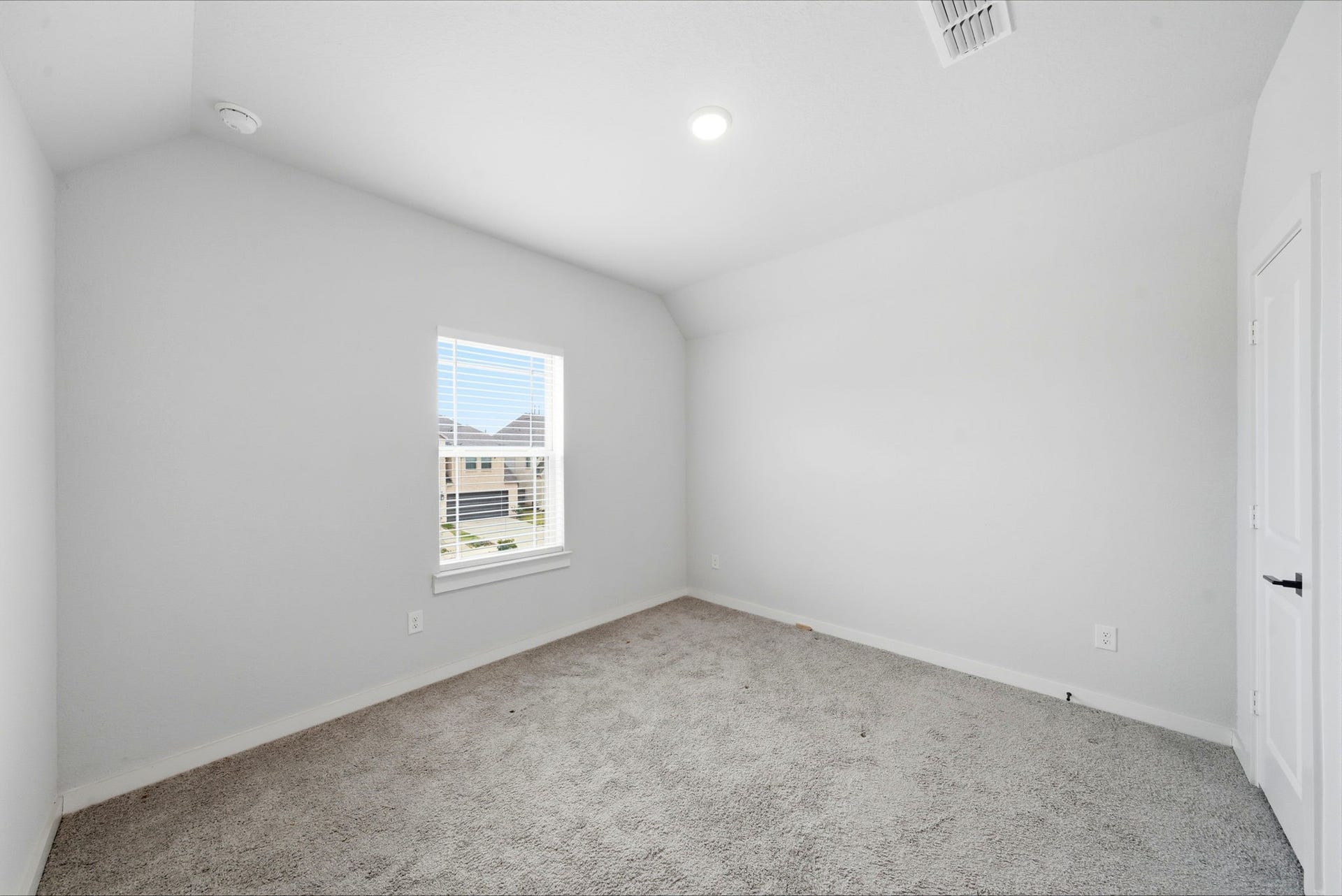 8815 Morning Glow Drive, Missouri City, TX 77459 This is a bright, carpeted room with neutral walls, featuring a single window providing natural light and a view of neighboring houses. It's ideal for a bedroom or office space.