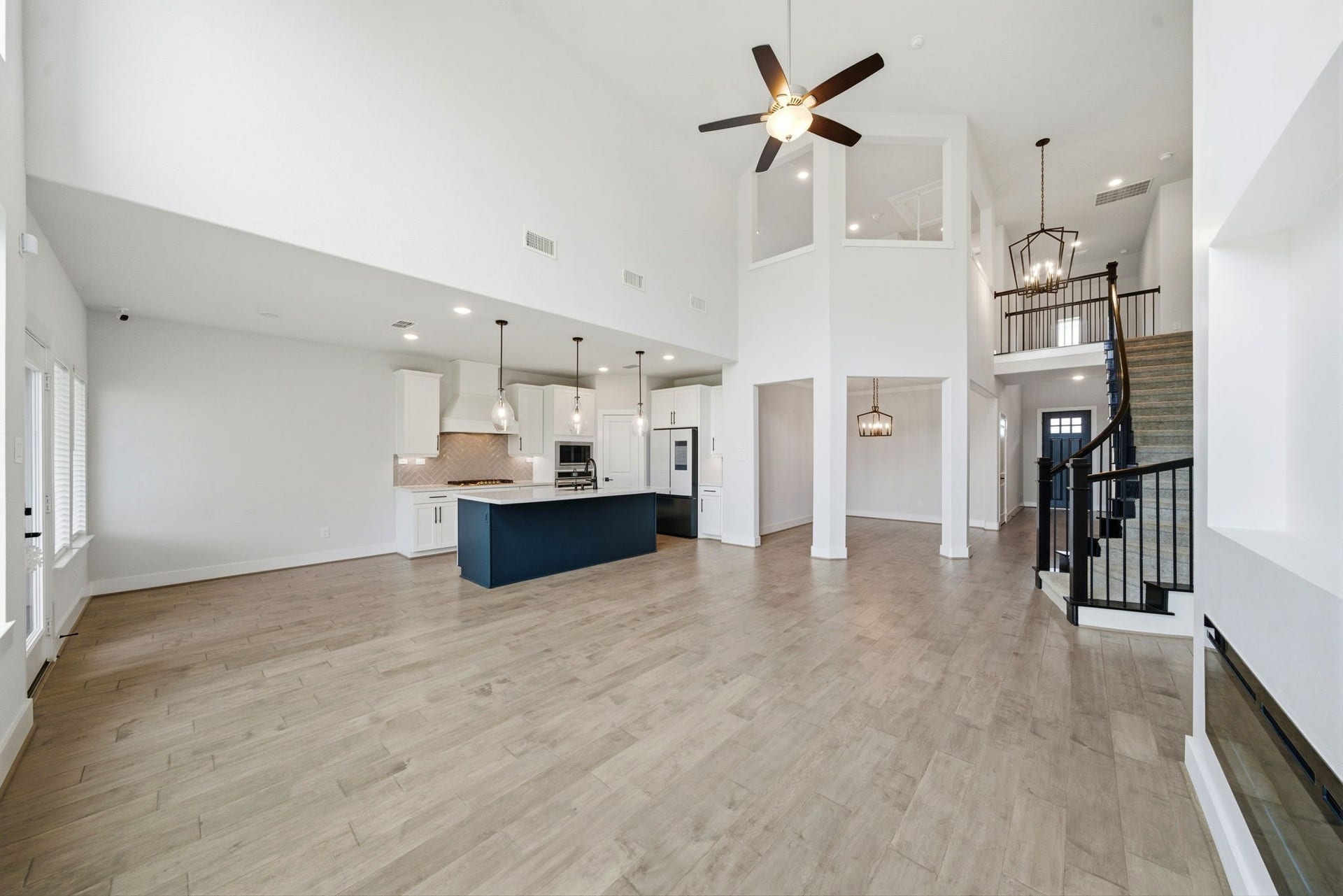 8815 Morning Glow Drive, Missouri City, TX 77459 This spacious open-concept living area features high ceilings, a modern kitchen with an island, and elegant light fixtures. Hardwood floors complement the bright, airy atmosphere, and a stylish staircase leads to the second floor. Perfect for entertaining and comfortable living.