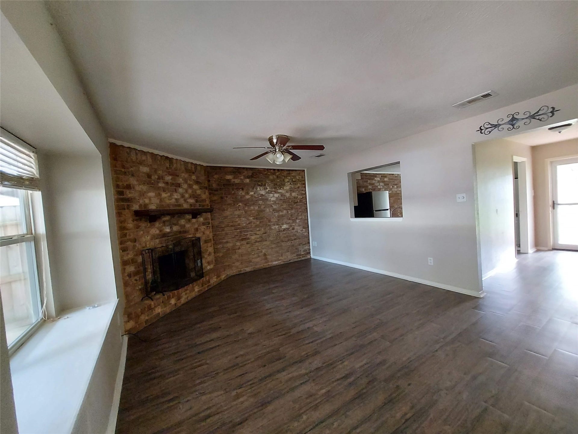 3878 Laura Leigh Drive, Friendswood, TX 77546 Spacious living room with a charming brick fireplace, elegant wood flooring, and ample natural light from large windows.