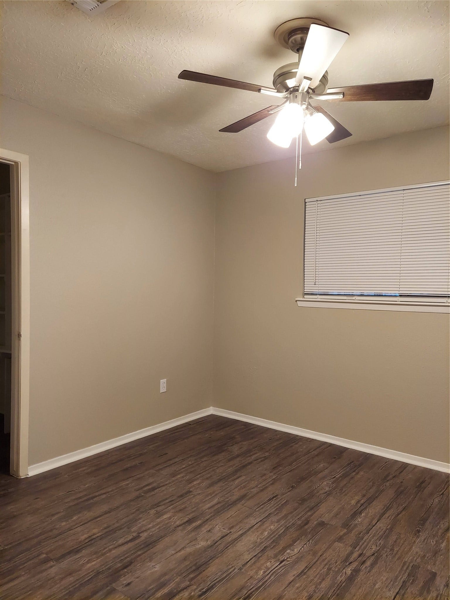 3878 Laura Leigh Drive, Friendswood, TX 77546 Cozy room with warm wooden floors, neutral walls, and a ceiling fan for comfort.