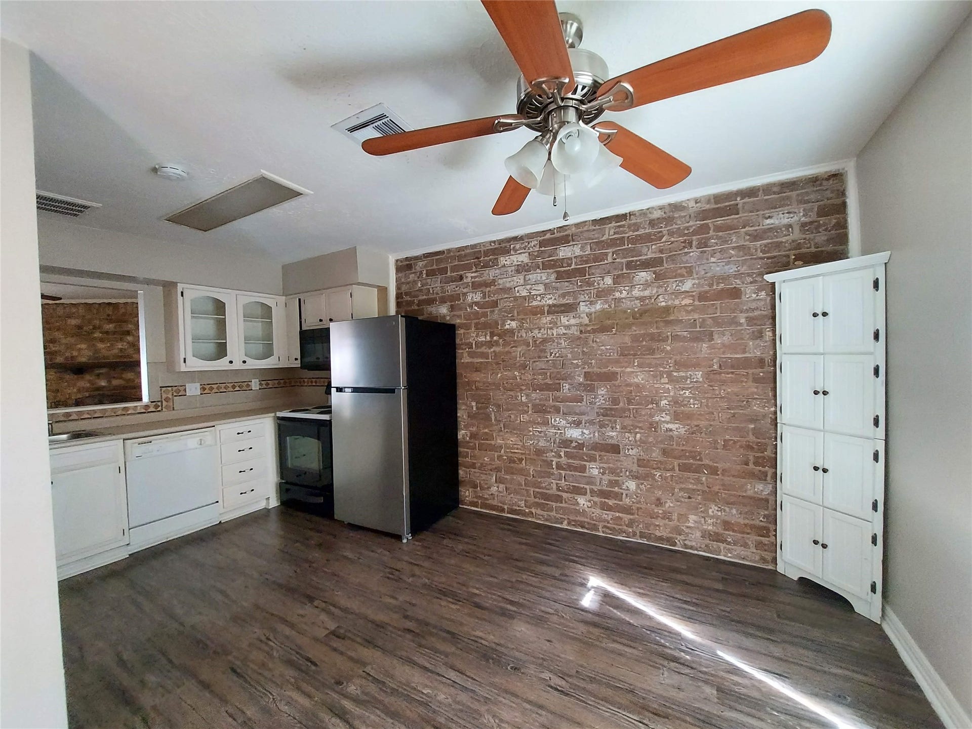 3878 Laura Leigh Drive, Friendswood, TX 77546 Charming kitchen with exposed brick accent wall, modern stainless steel appliances, and stylish wood flooring.