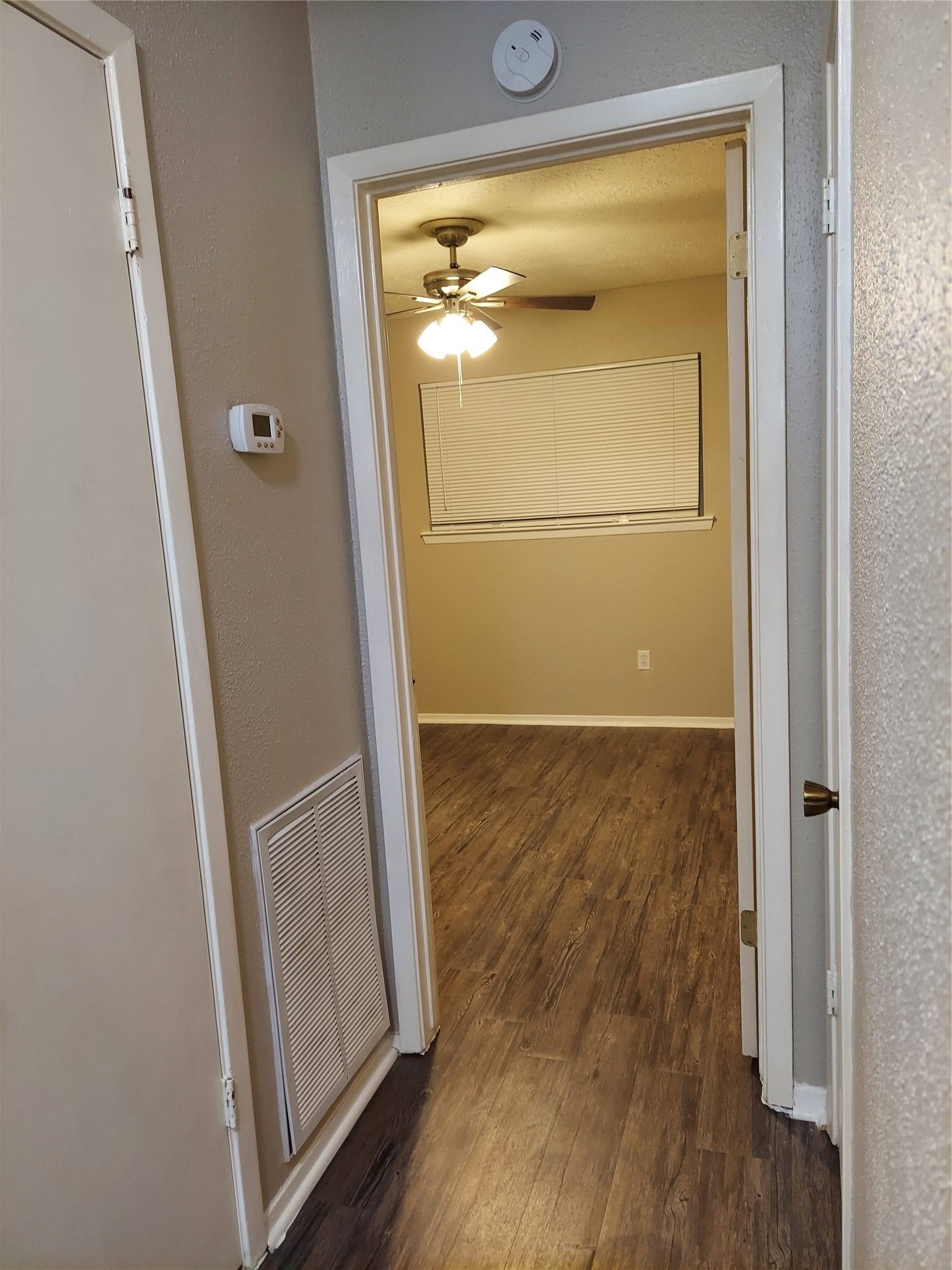 3878 Laura Leigh Drive, Friendswood, TX 77546 Charming hallway leads to a cozy room featuring warm wood flooring and a ceiling fan, creating a welcoming atmosphere.