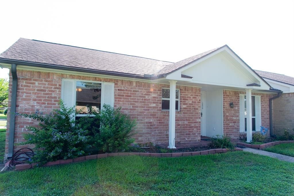 3878 Laura Leigh Drive, Friendswood, TX 77546 Charming brick exterior with a welcoming front porch, framed by lush greenery and a well-maintained lawn.