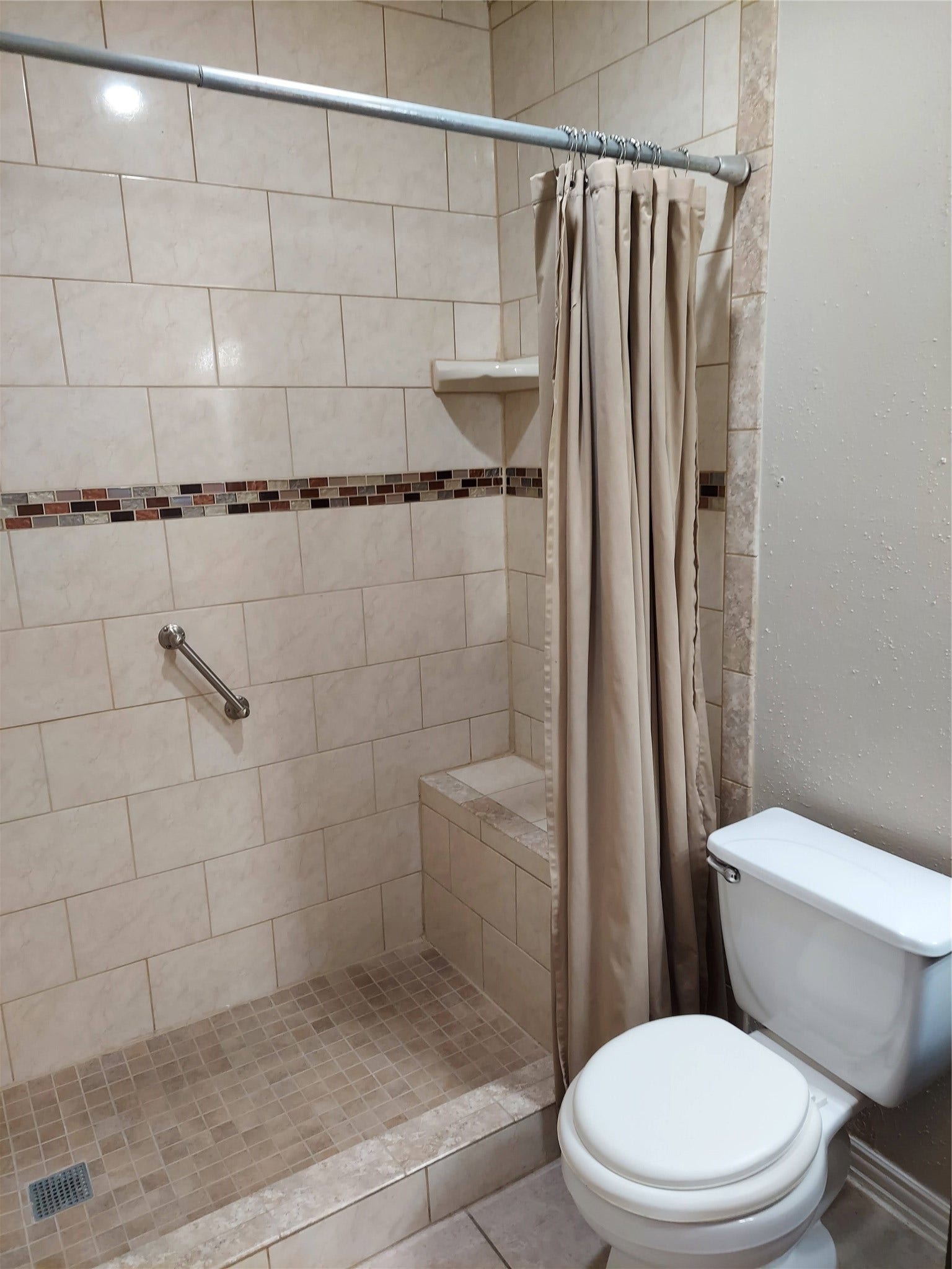 3878 Laura Leigh Drive, Friendswood, TX 77546 Elegant bathroom featuring a spacious walk-in shower with decorative tile accents, a convenient grab bar, and a neutral color palette for a relaxing atmosphere.