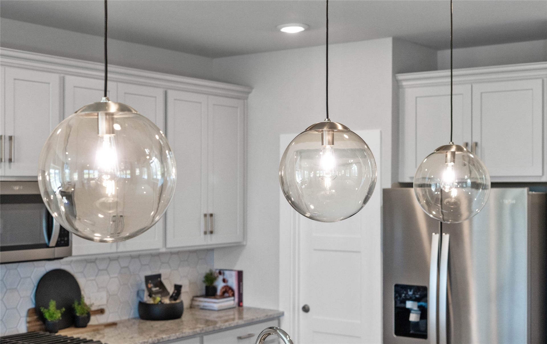 19608 Montgomery Ridge Way, Montgomery, TX 77316 Atwell Pendant Brushed Nickel lights that hang over the kitchen island.