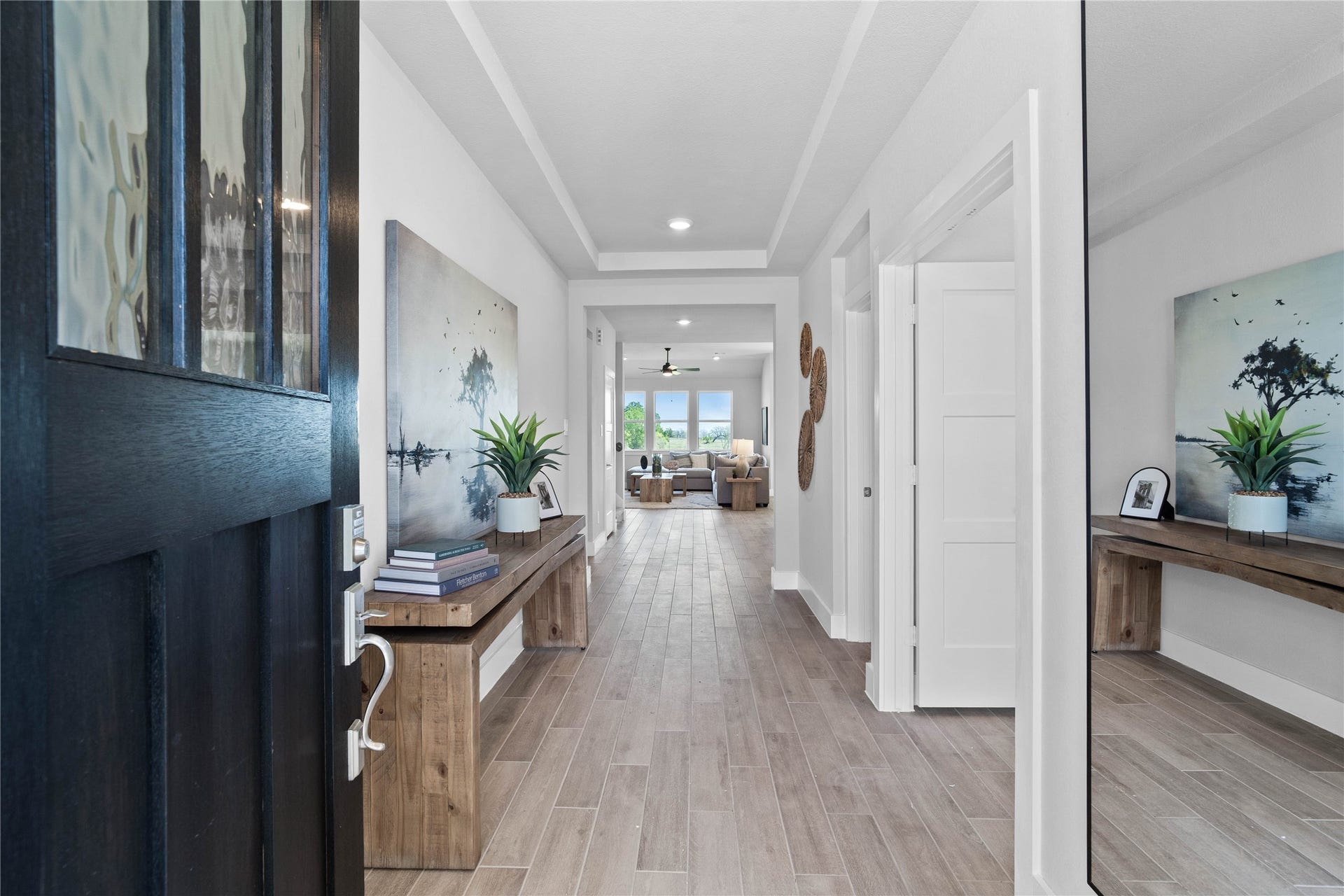 19608 Montgomery Ridge Way, Montgomery, TX 77316 This entryway features a modern, open-concept design. The long, wide, and bright corridor utilizes a neutral color palette, recessed lighting, and wood-look tile flooring to lead the eye toward the home's main living area.