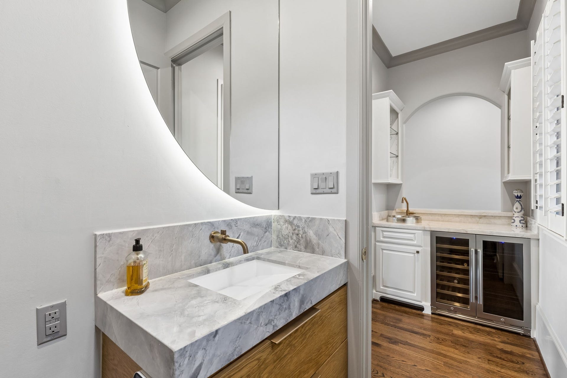 The powder room measures approximately 6' x 4'10" and offers a Quartzite countertop and contemporary square sink that provide a sleek, modern aesthetic along with the elegant vanity with 2 deep drawers. An automatic high-end toilet and half-moon mirror adds an extra touch of luxury.