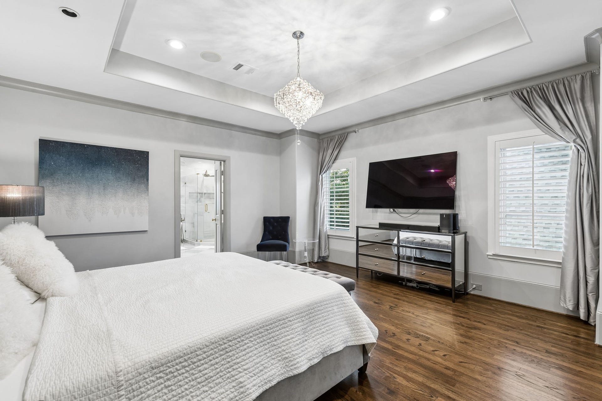 Large windows, recessed lighting, and a sparkling tiered crystal chandelier create a bright and luxurious atmosphere