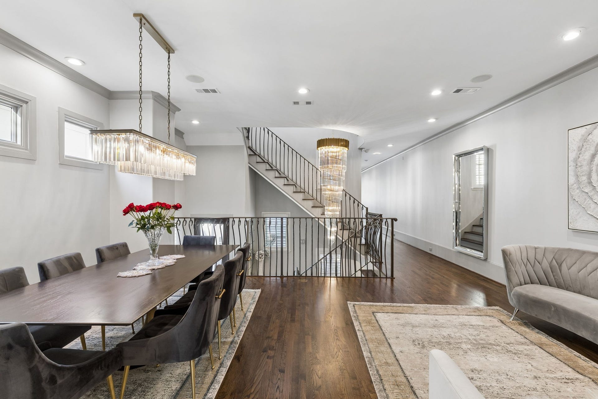 The open-concept dining and sitting areas are beautifully framed by an elegant staircase and illuminated by a spectacular cascading crystal chandelier, enhancing the home's grand scale and timeless sophistication.
