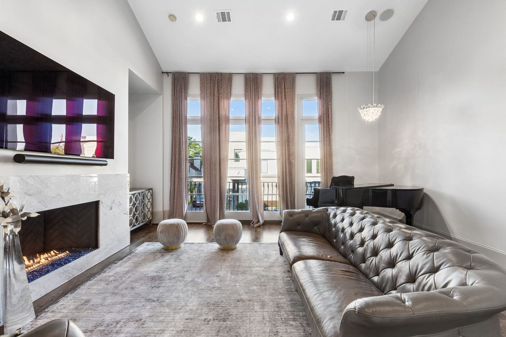 Large vertical windows framed by custom curtains fill the room with natural light while highlighting the beautiful gas fireplace with Marble and 2 cut outs the flank the fireplace.