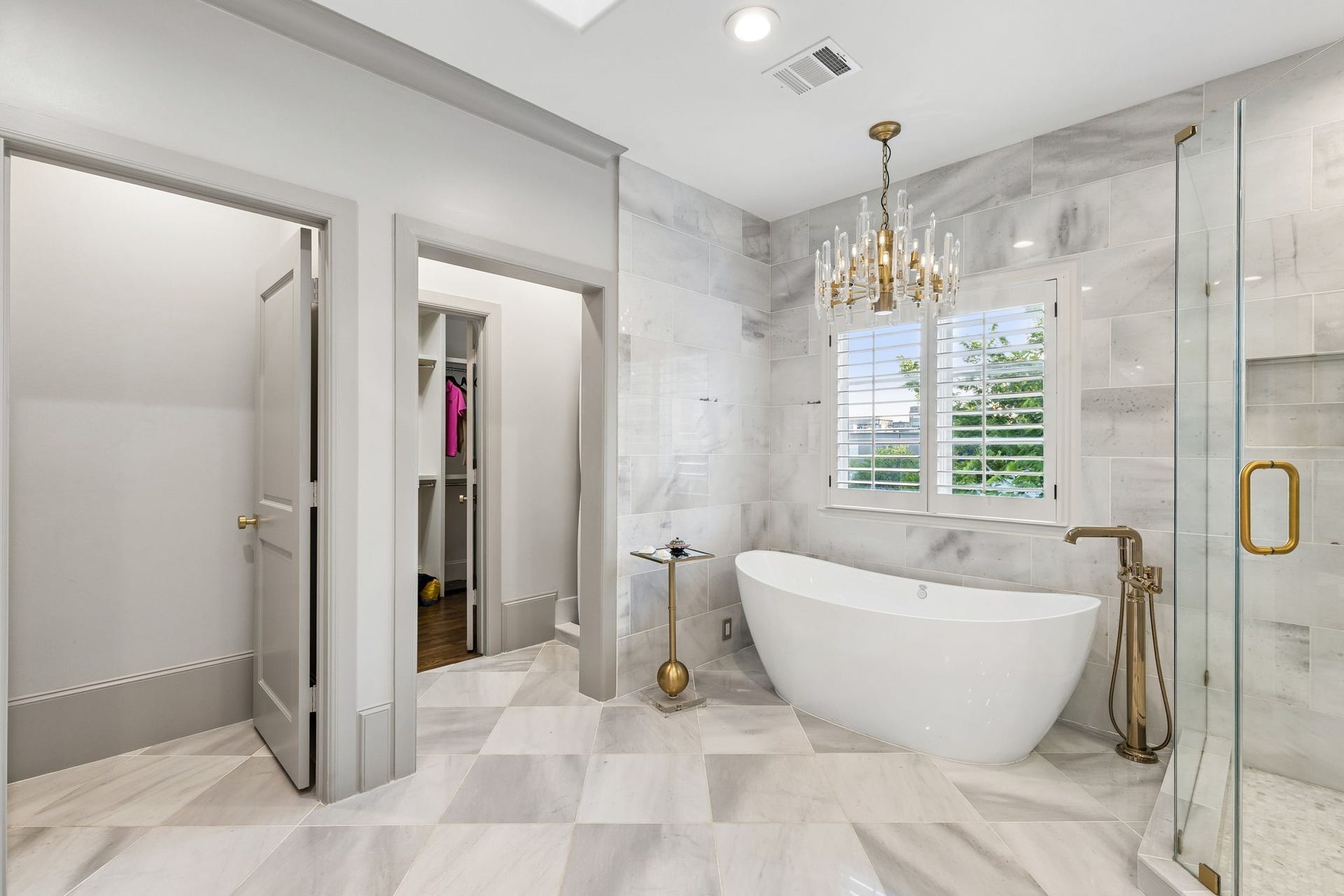 Relax in the soaking tub complemented by modern brass and glass chandelier or enjoy the frameless marble shower with marble surround, elegant brass accents and rain showerhead.